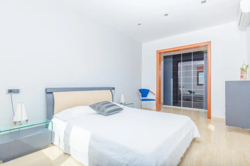 Un dormitorio luminoso con una cama tendida y un armario con puertas de vidrio.