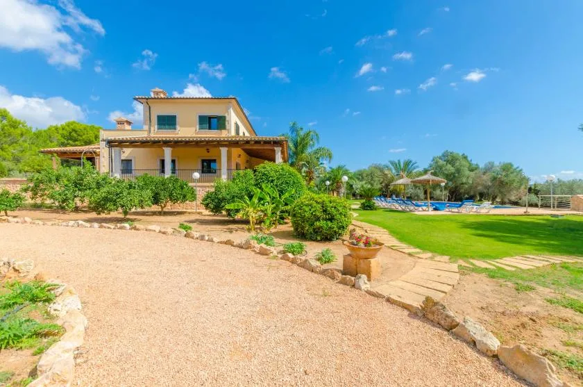 Una casa está junto a un jardín y césped bajo un cielo azul despejado.