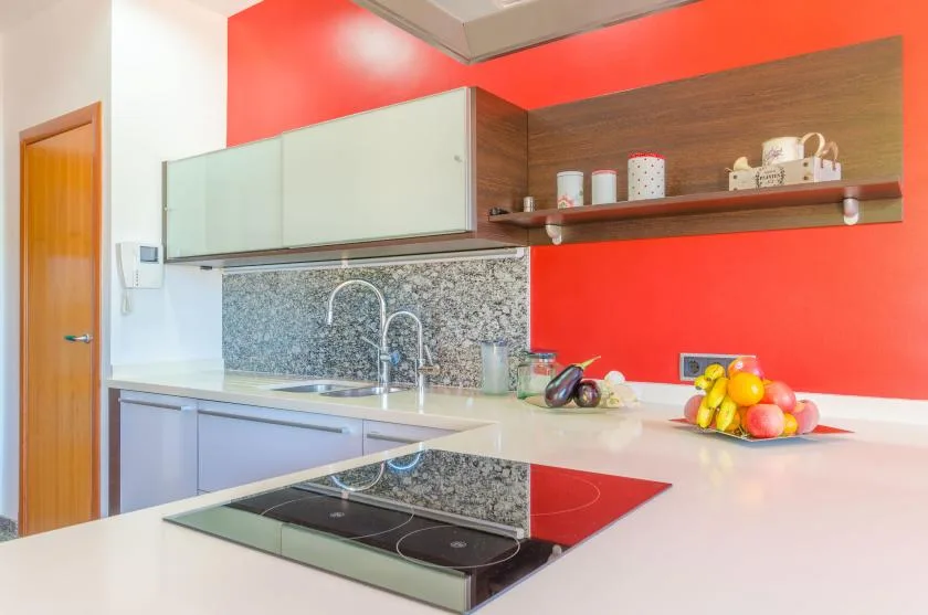 Una cocina luminosa con una placa de cocina y un frutero sobre la encimera.