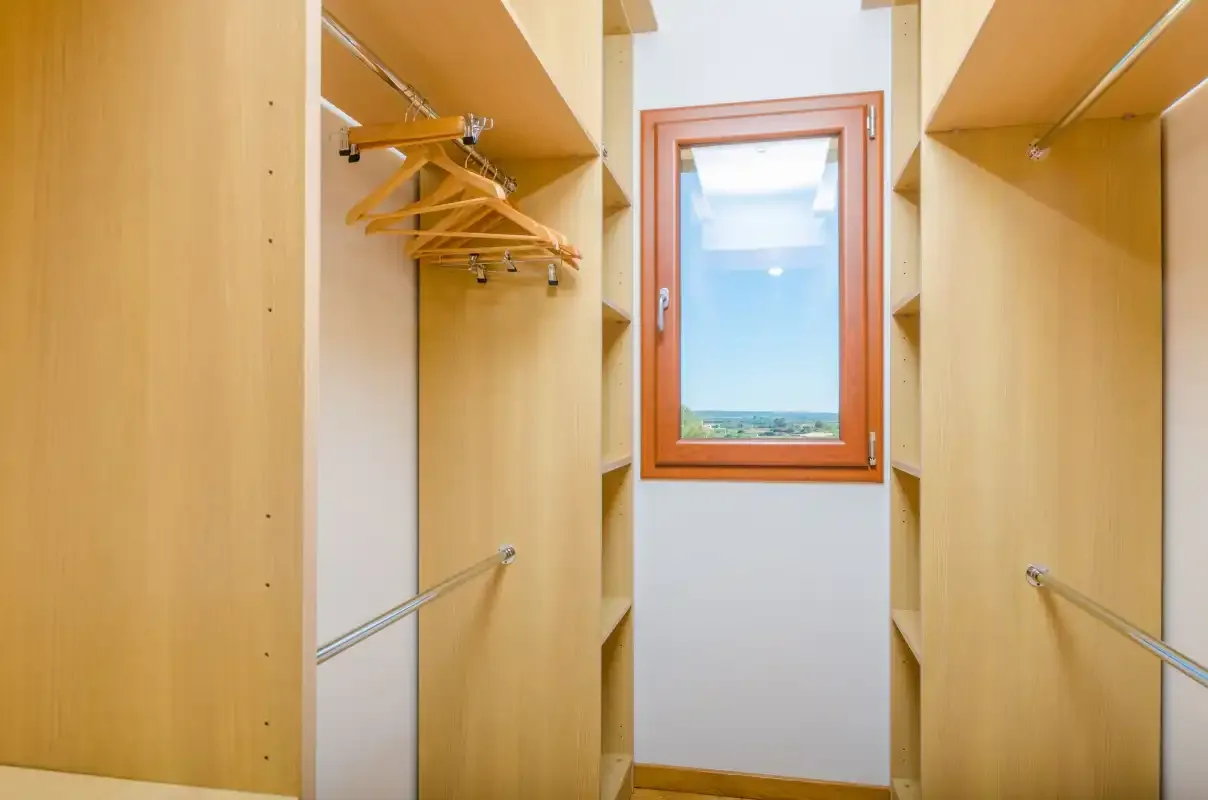 Un vestidor con estantes de madera y una ventana con vistas al paisaje.