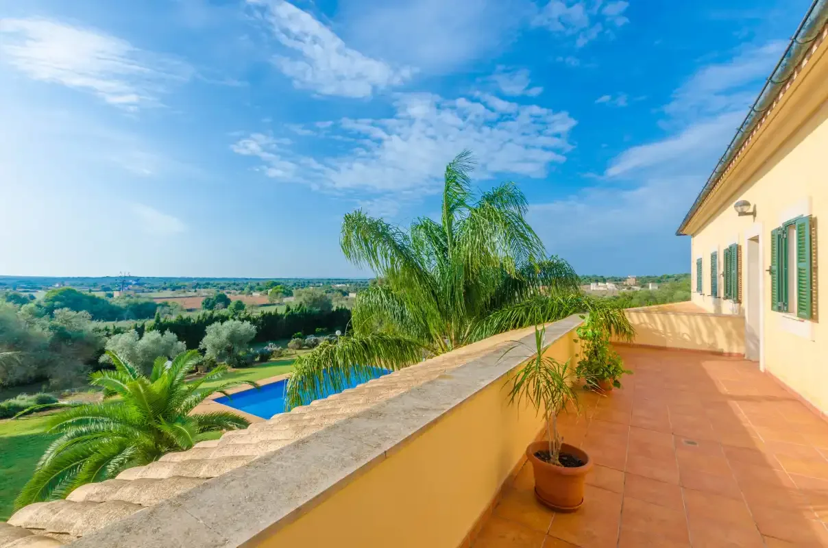Una terraza soleada da a una piscina y al campo verde.
