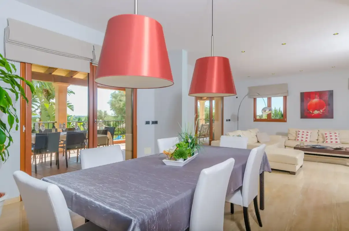 Comedor con una mesa y lámparas colgantes rojas junto a la sala de estar.