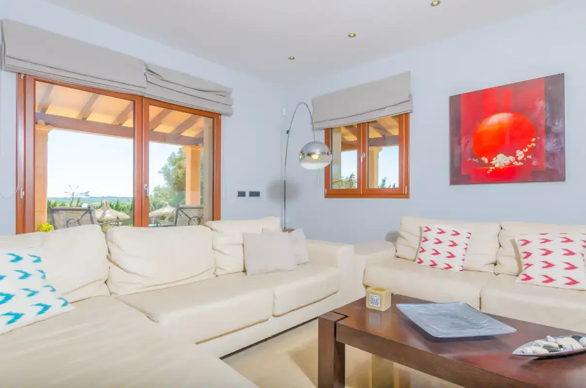 Un salón luminoso con asientos color crema y grandes ventanas.