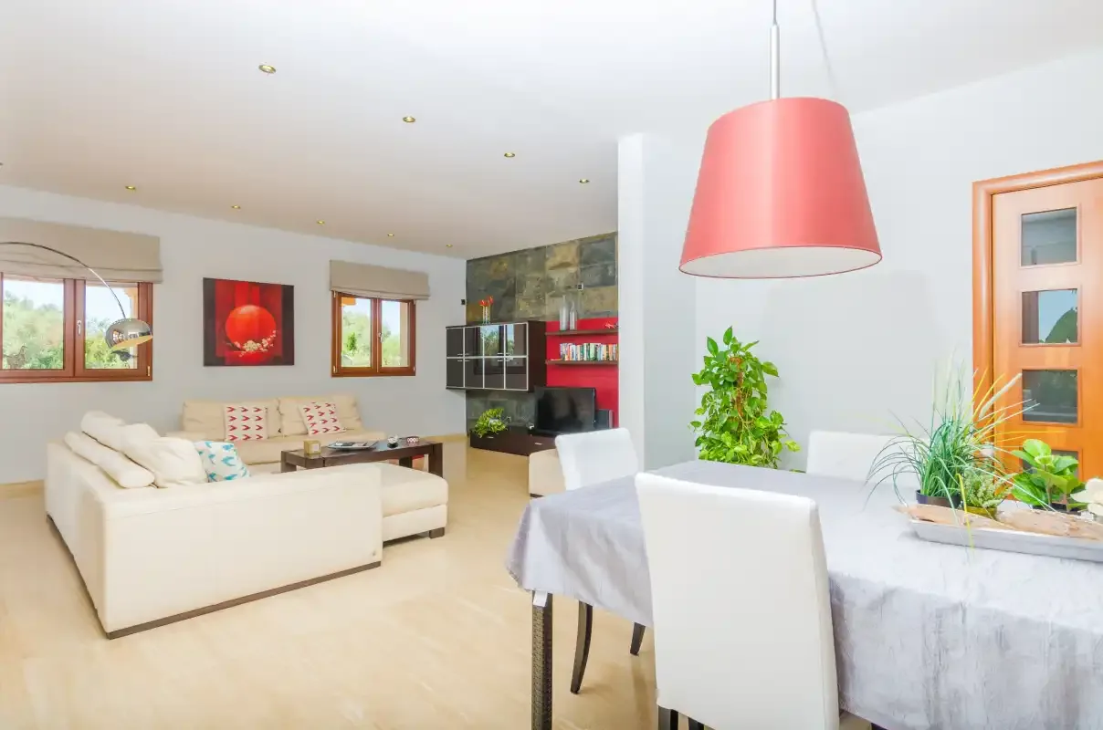 Una sala de estar y comedor diáfana con asientos blancos y una mesa.