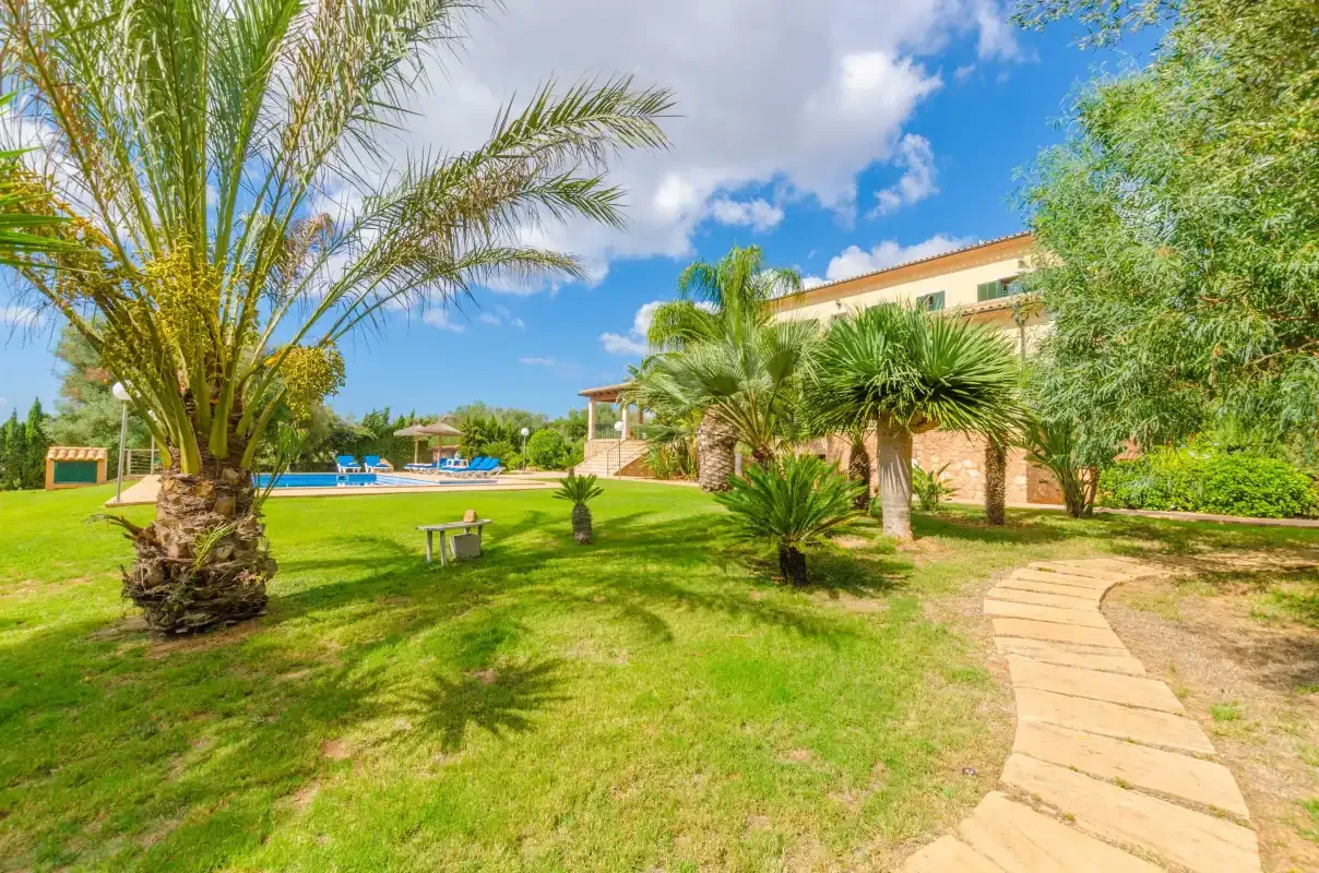 Un jardín con palmeras y un sendero de piedra junto a un edificio.