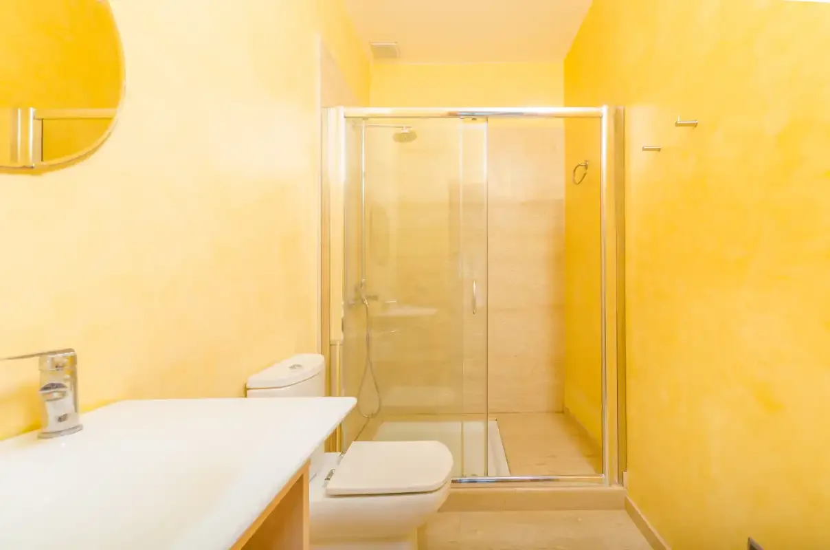 Un baño con ducha de cristal, inodoro y lavabo.