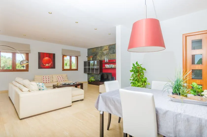 Sala de estar y comedor de planta abierta, con asientos claros y una mesa puesta.