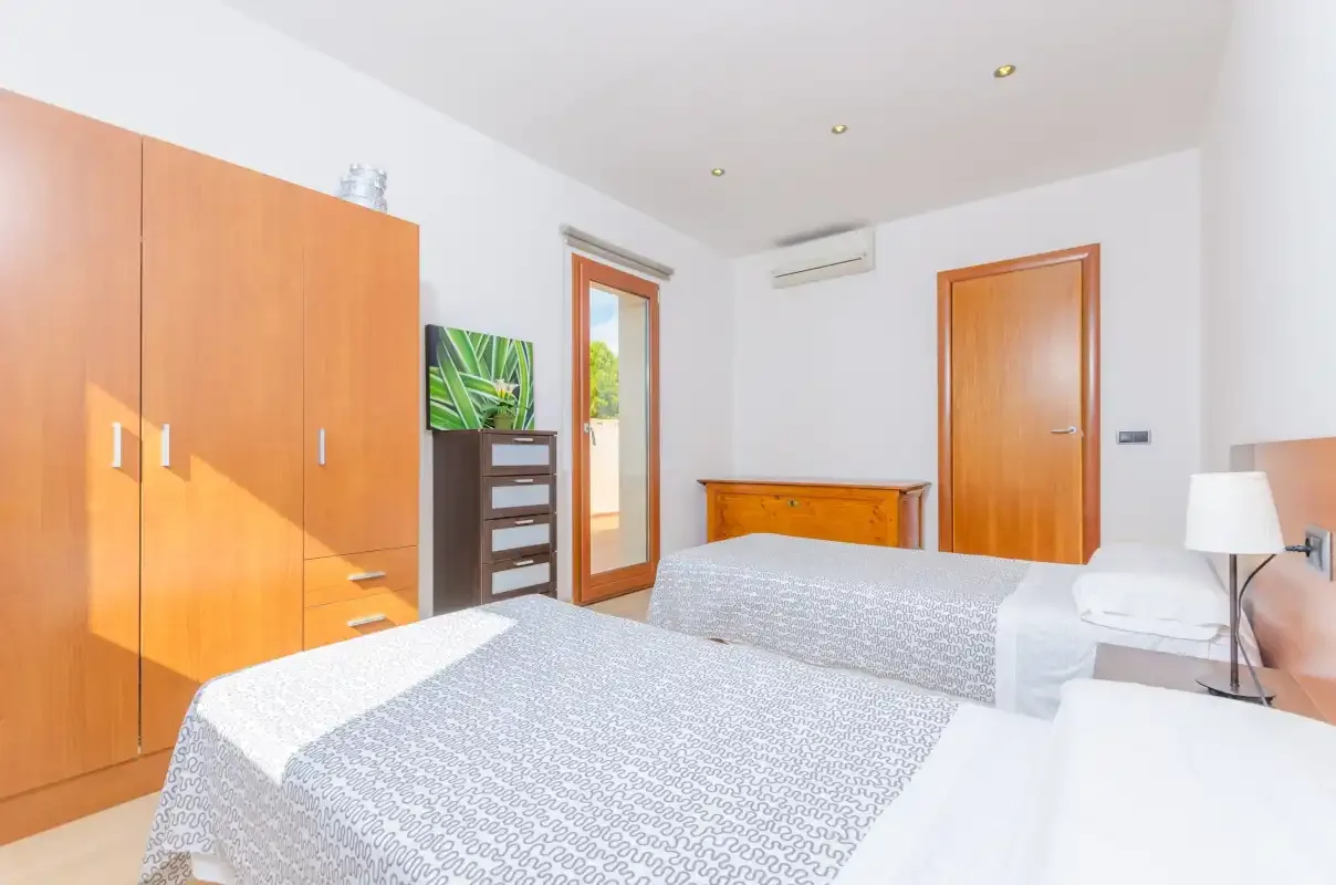 Un dormitorio con dos camas, un armario de madera y una cómoda pequeña.