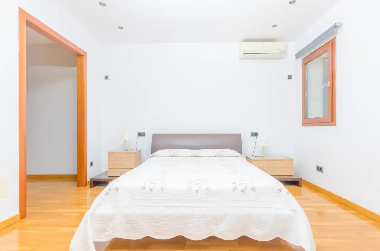 Un dormitorio luminoso con una cama entre dos mesitas de noche.