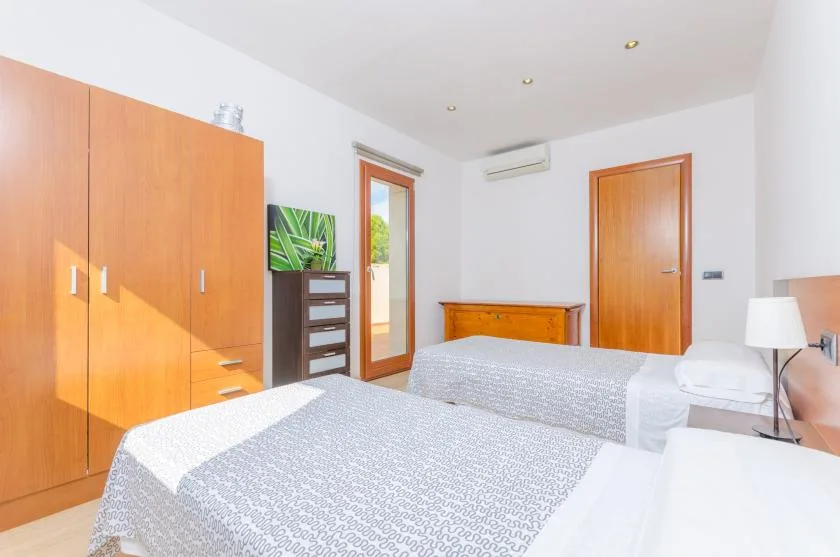 Un dormitorio luminoso con dos camas, armarios de madera y una ventana.