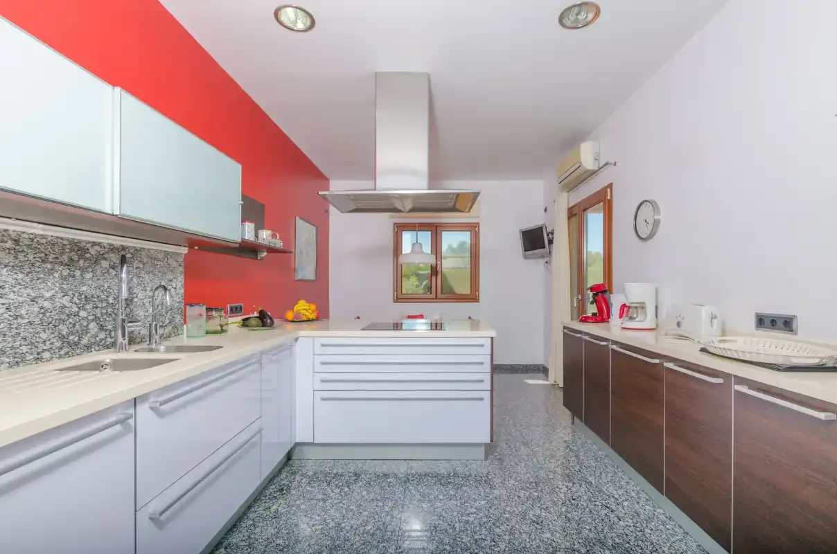 Una cocina moderna con armarios claros y oscuros y una zona de cocción central.