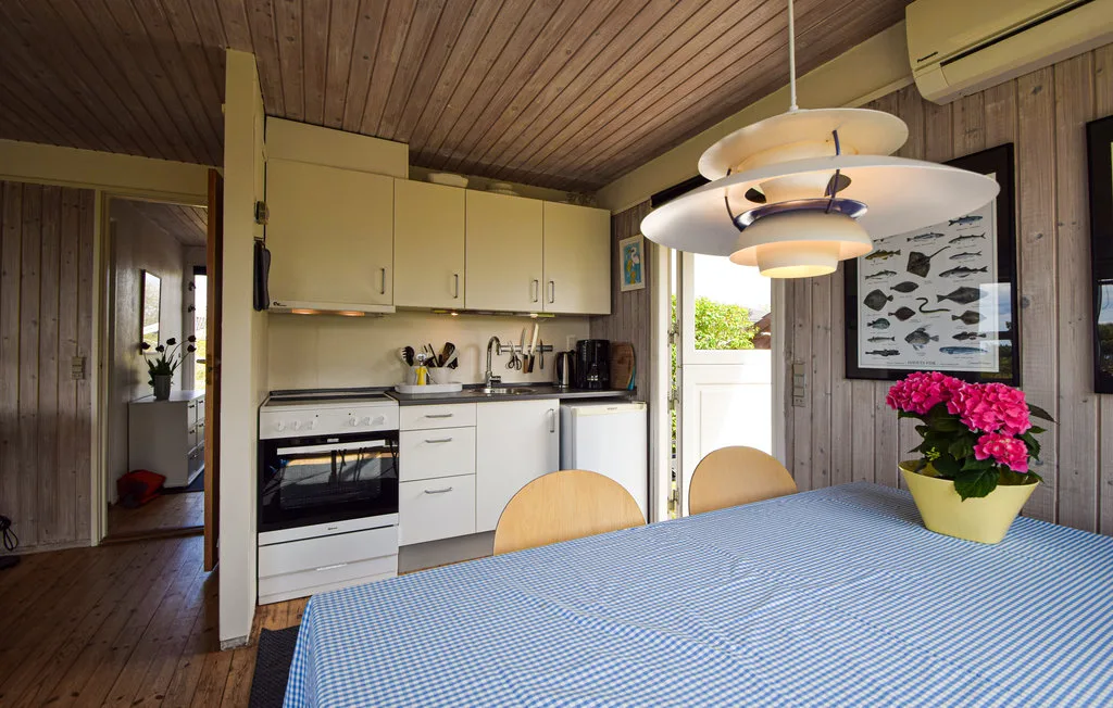A compact kitchen with white cabinets and a dining table in the foreground.