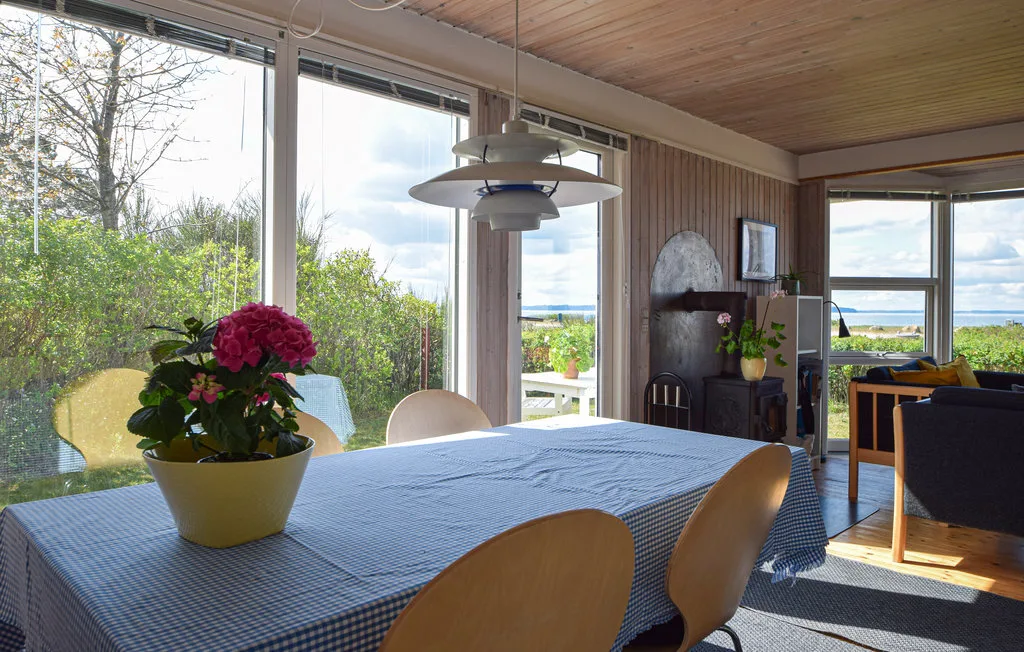 A dining area with a set table and large windows overlooking greenery.