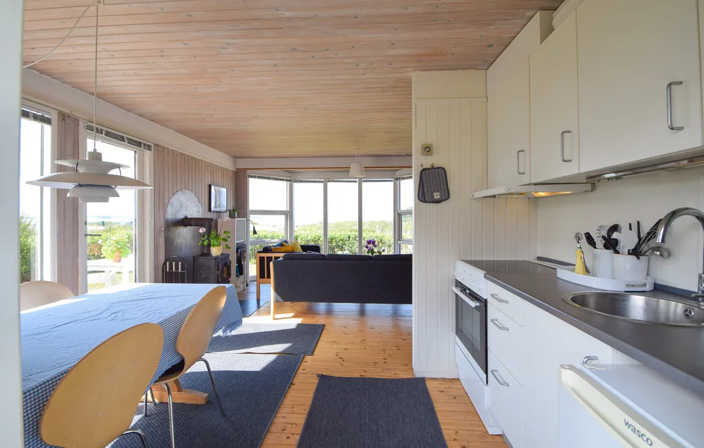 A bright open-plan room combines a kitchen, dining area, and living space.