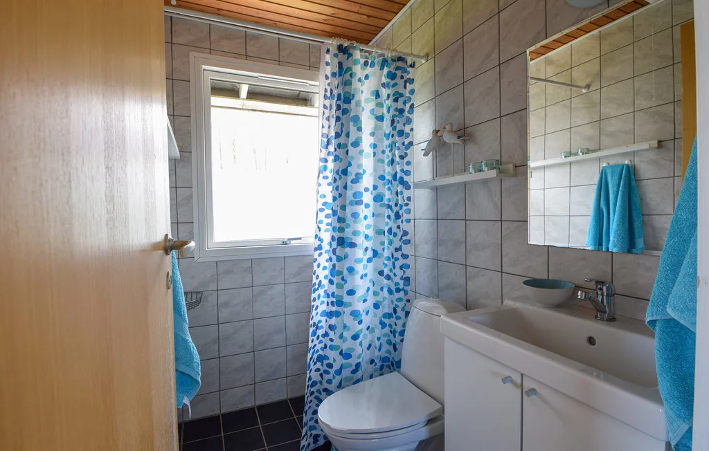 A tiled bathroom with a bathtub, sink, and patterned shower curtain.