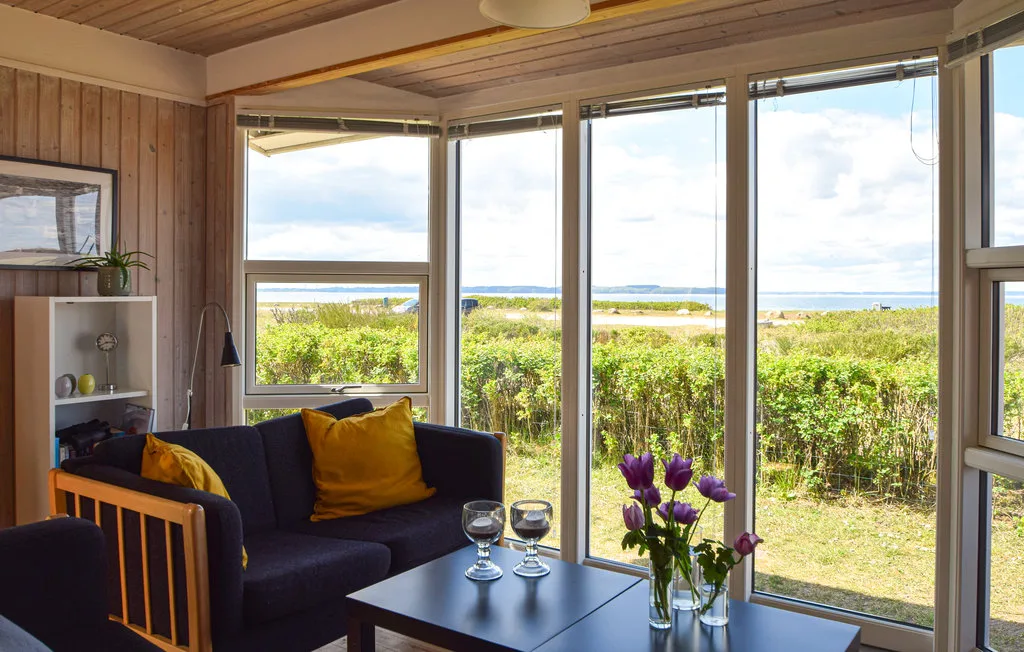 A living room with seating beside large windows overlooking greenery and water.