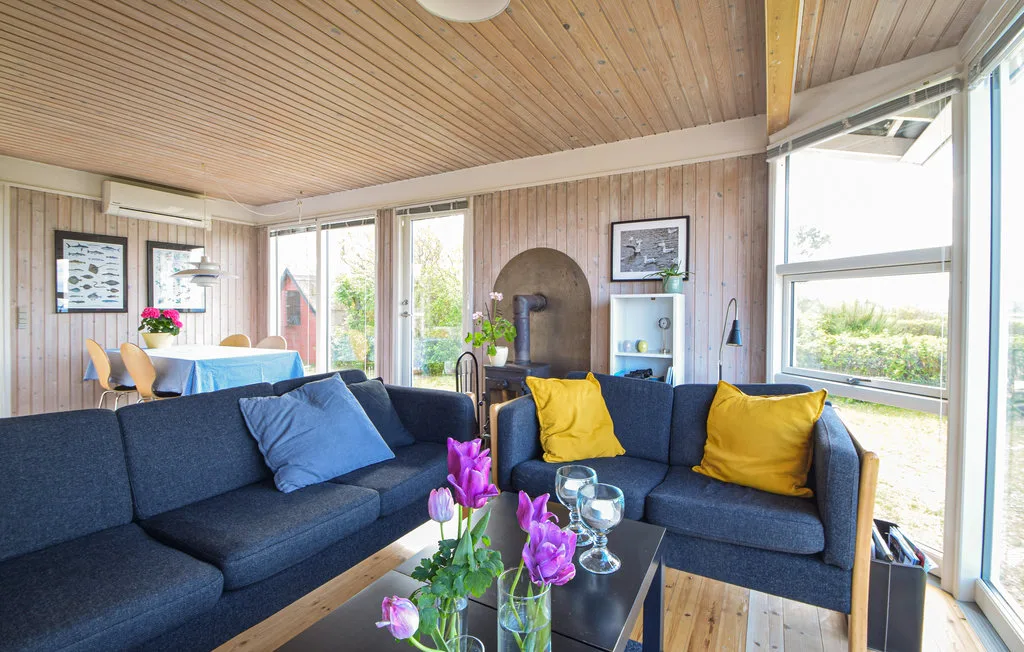 A living room with blue seating, yellow cushions, and large windows.