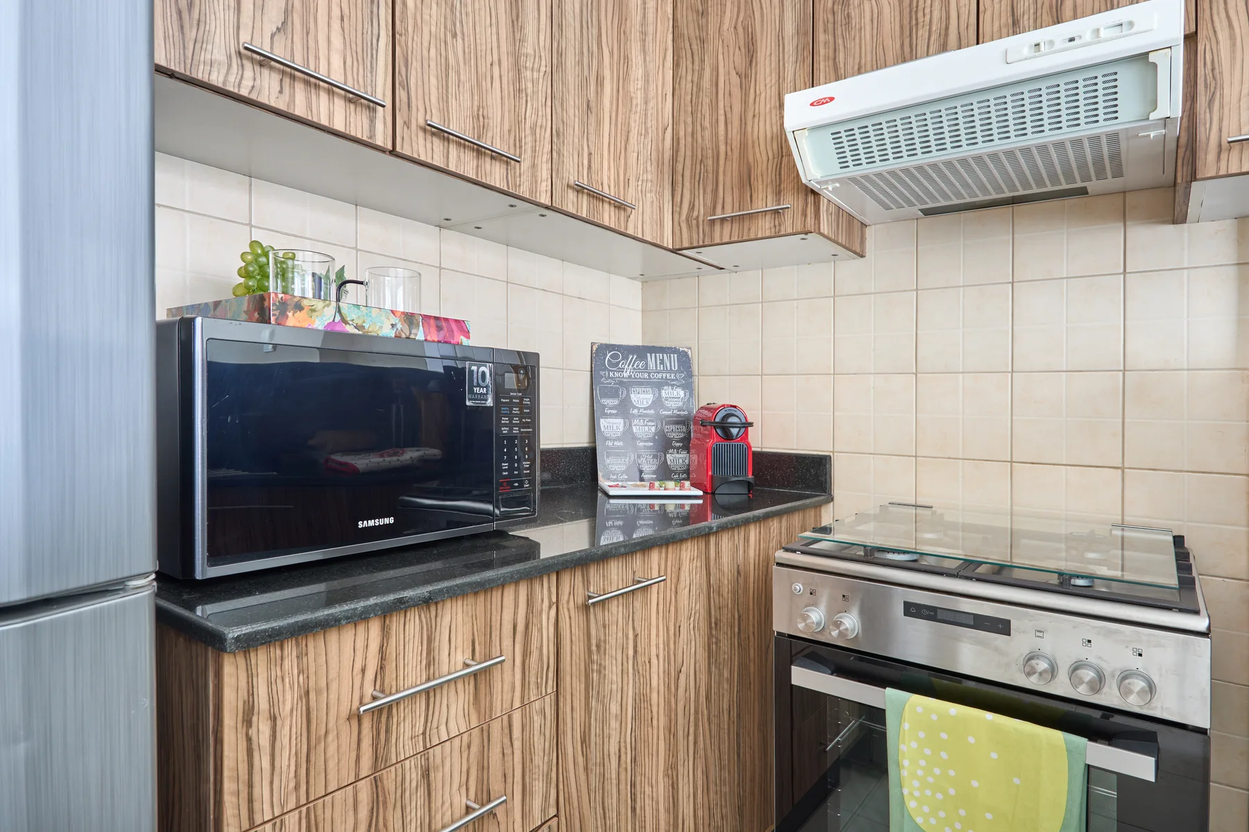Una cocina compacta con gabinetes de veta de madera, microondas y estufa.