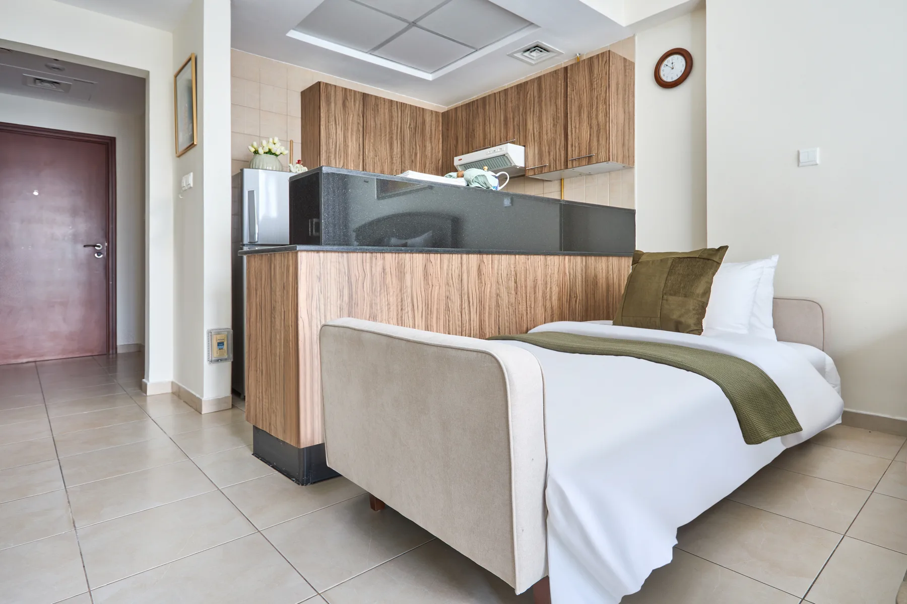 Un dormitorio con una cama bien tendida junto a un mostrador revestido de madera.