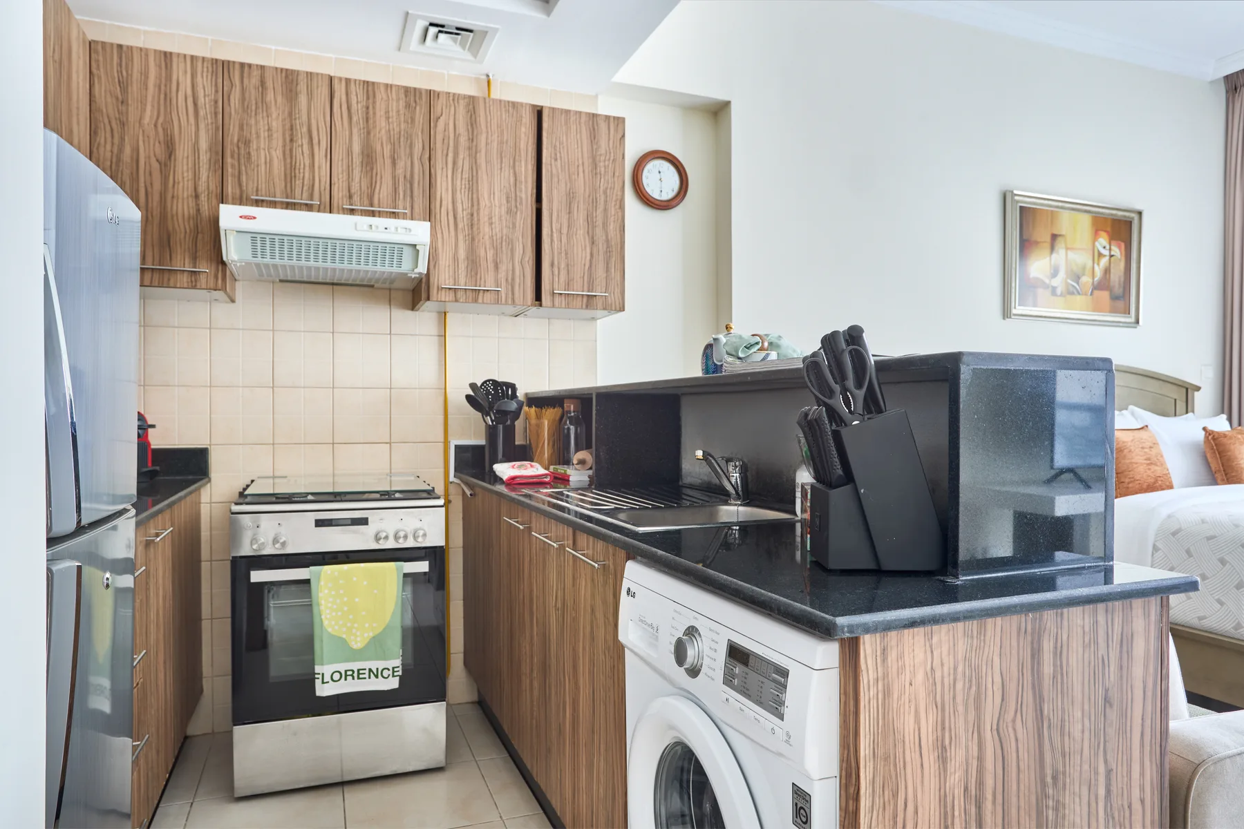 Una cocina compacta con armarios de madera, horno y lavadora.