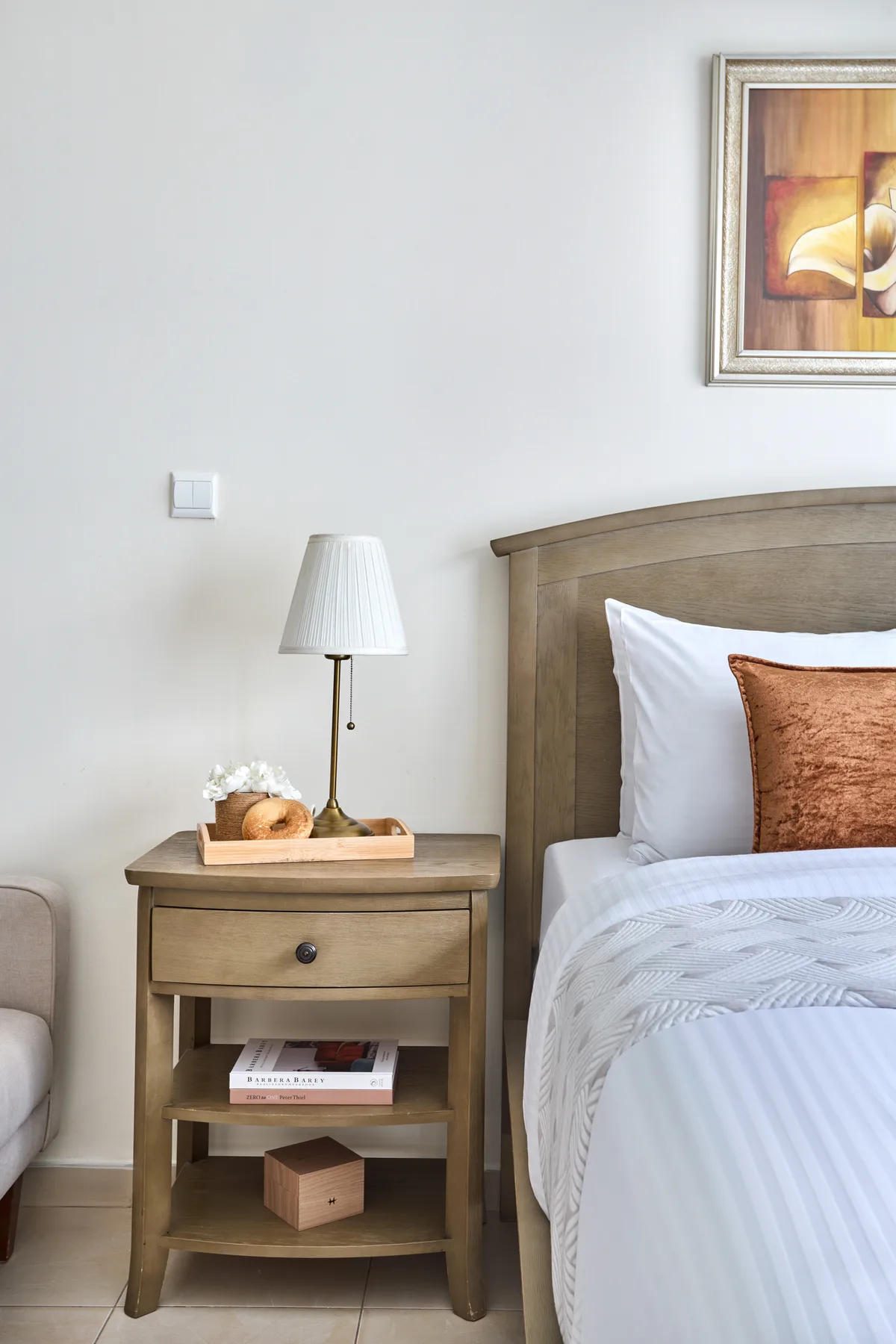 Un dormitorio con una mesita de madera junto a una cama bien tendida.