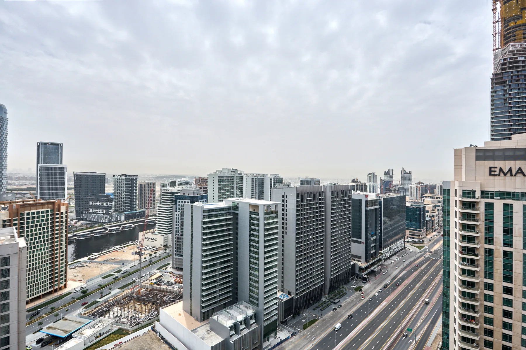 Un horizonte urbano con edificios altos y una vía de varios carriles bajo un cielo nublado.