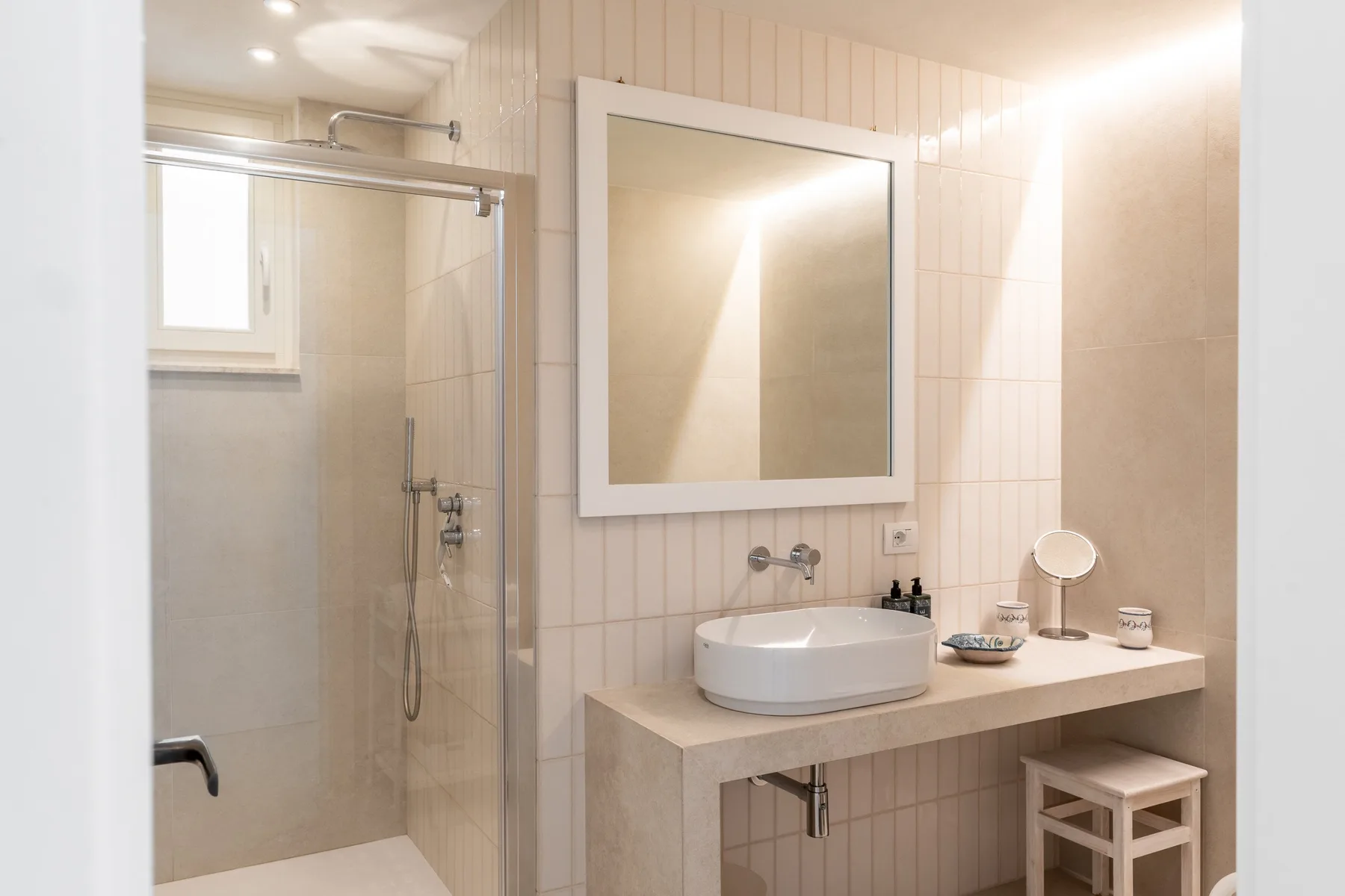 Un baño luminoso con ducha y lavabo debajo de un espejo grande.