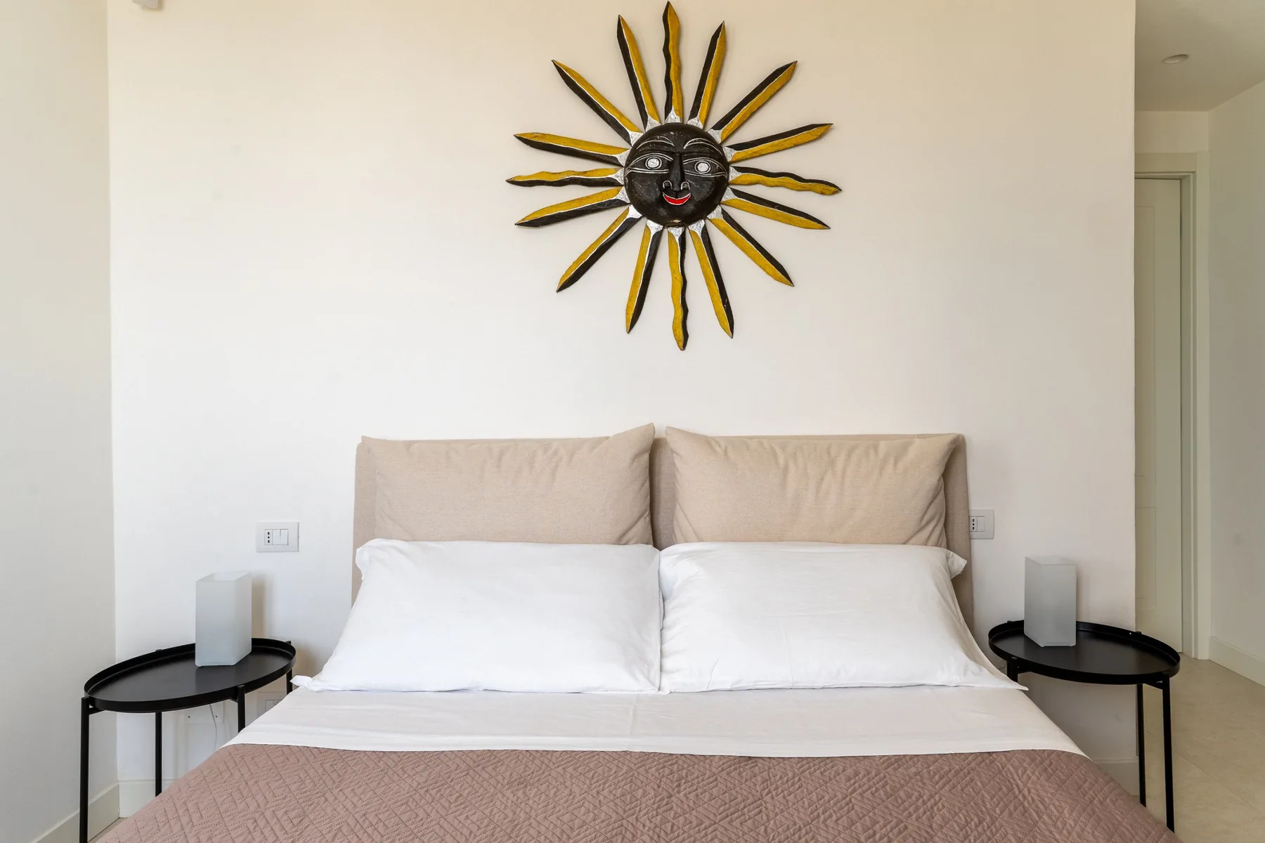 Un dormitorio con una cama bien tendida y una decoración mural en forma de sol.