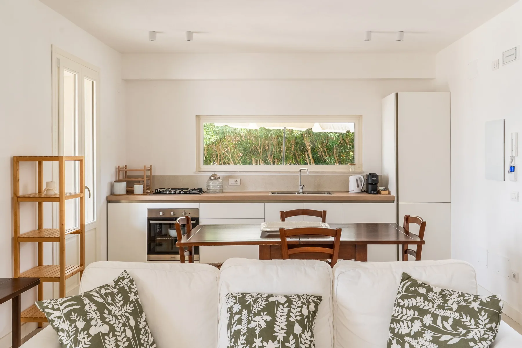 Una luminosa sala de estar y cocina diáfana, con una mesa de comedor detrás del sofá.