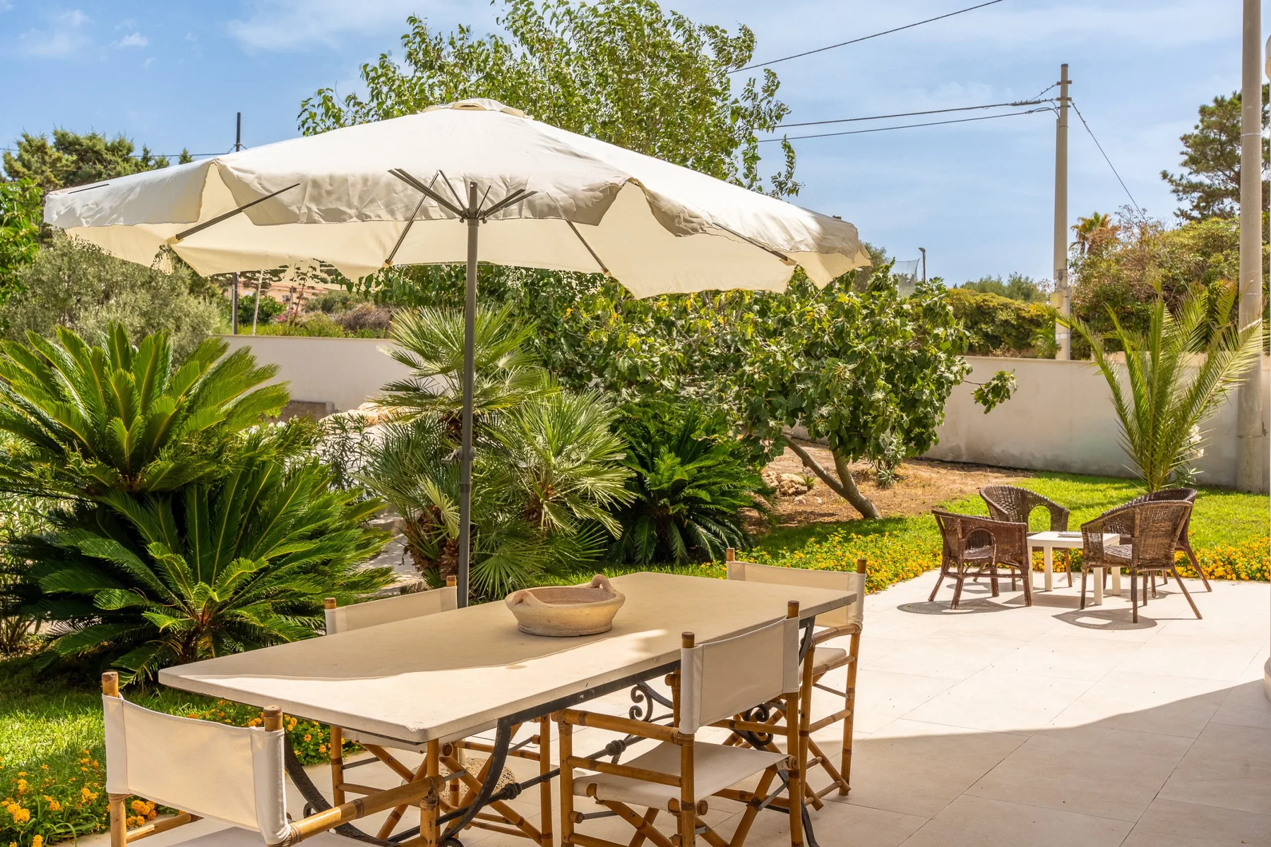 Un patio al aire libre con una gran sombrilla que da sombra a una mesa y sillas.