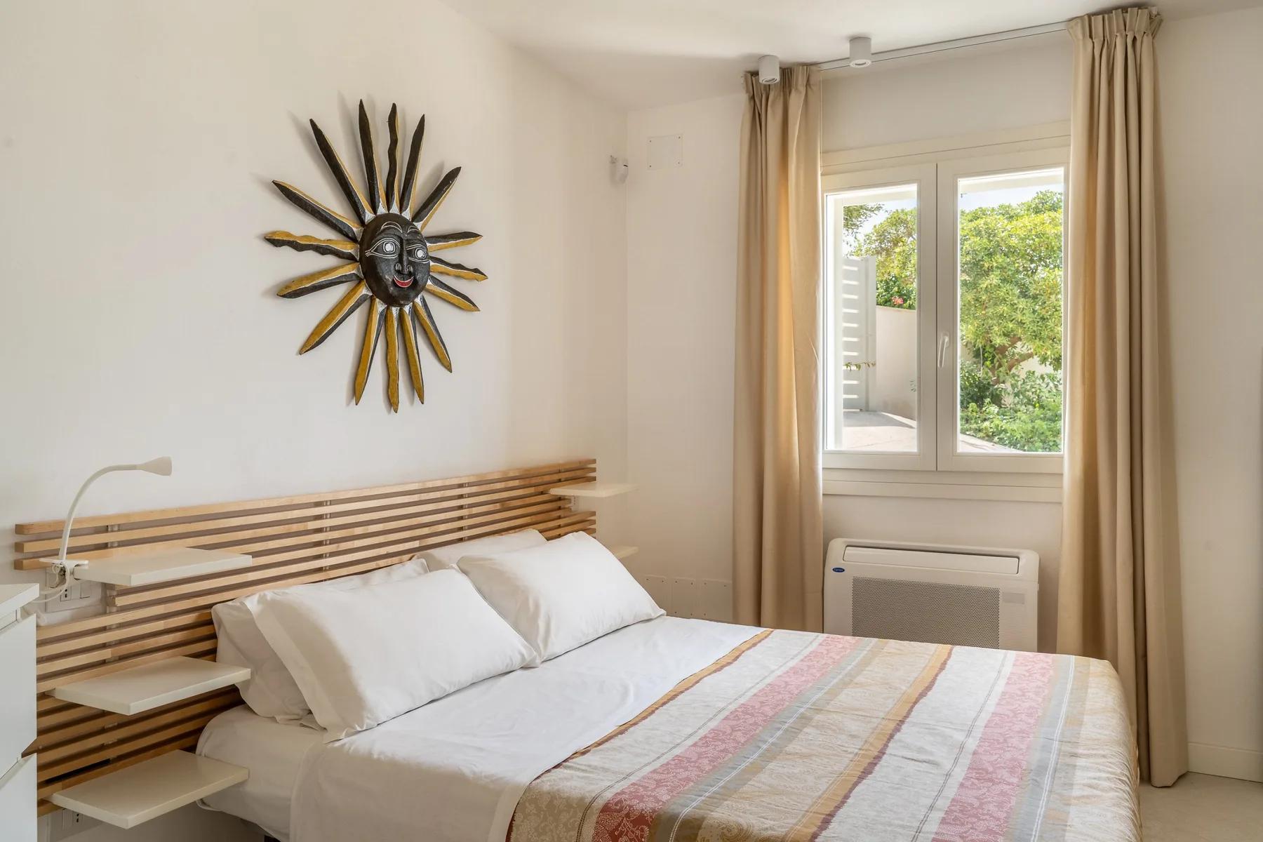 Un dormitorio con una cama bajo un reloj decorativo y junto a una ventana.