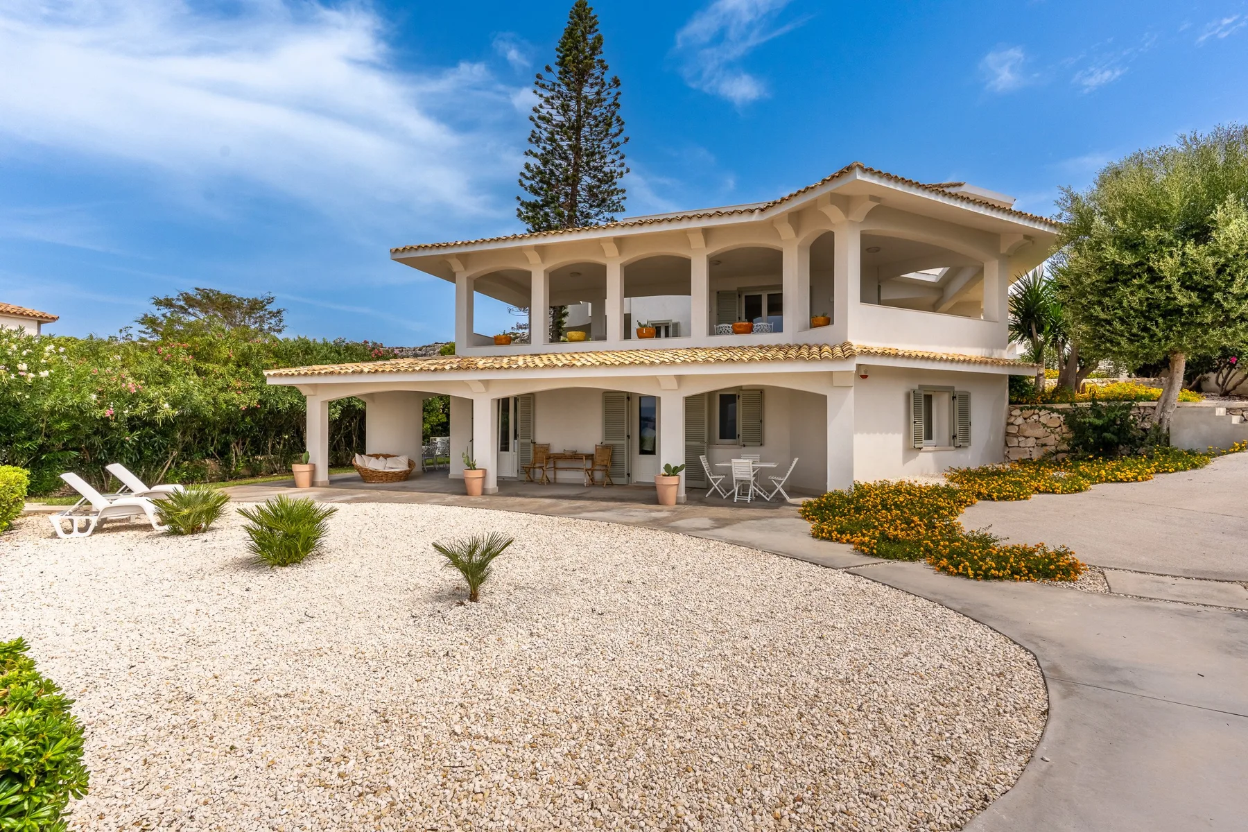 Una casa de dos plantas con patio cubierto y jardín de grava.