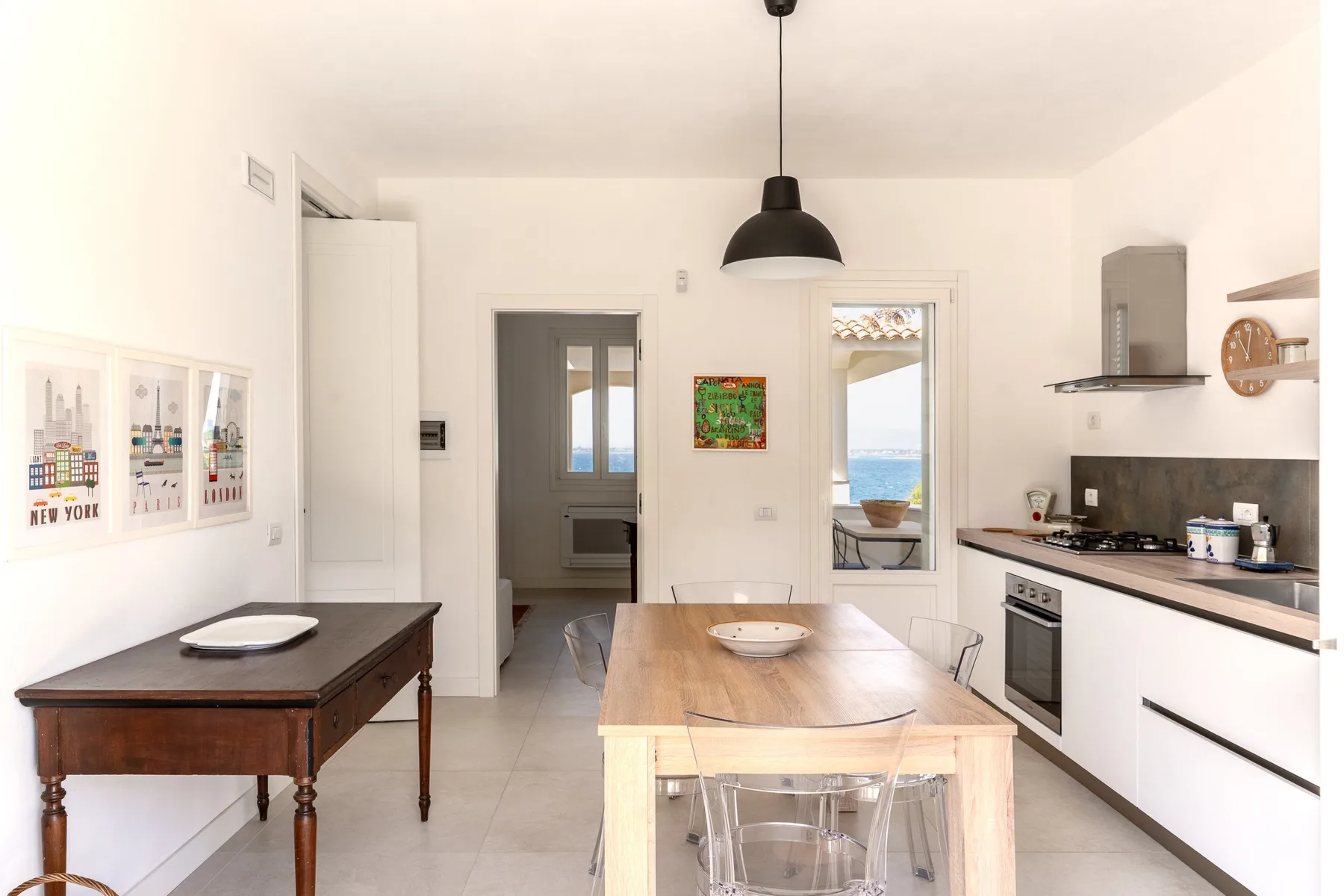 Una cocina luminosa con una mesa de comedor de madera y vistas al mar por la ventana.