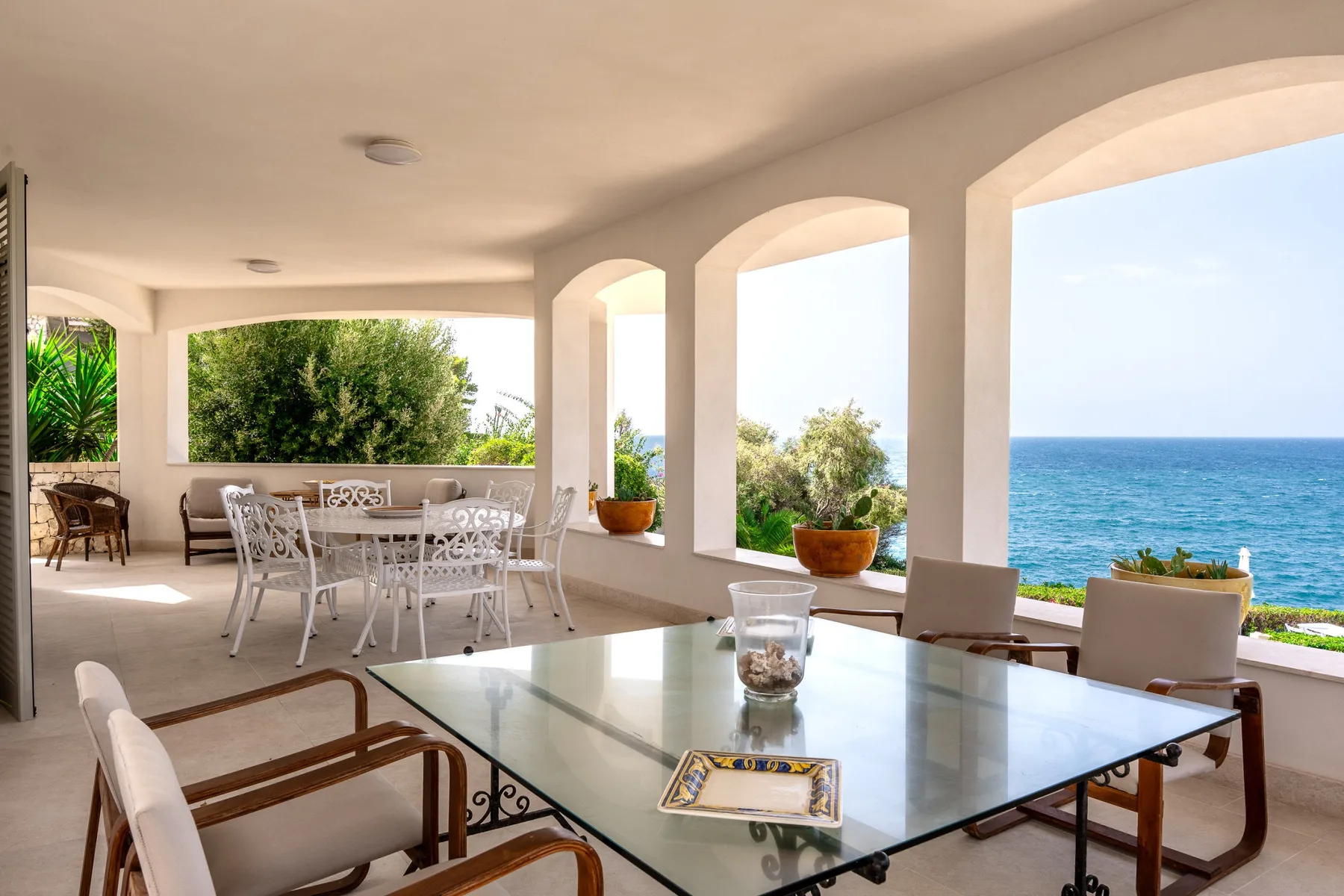 Una zona de comedor en una terraza cubierta se abre a una vista del mar.