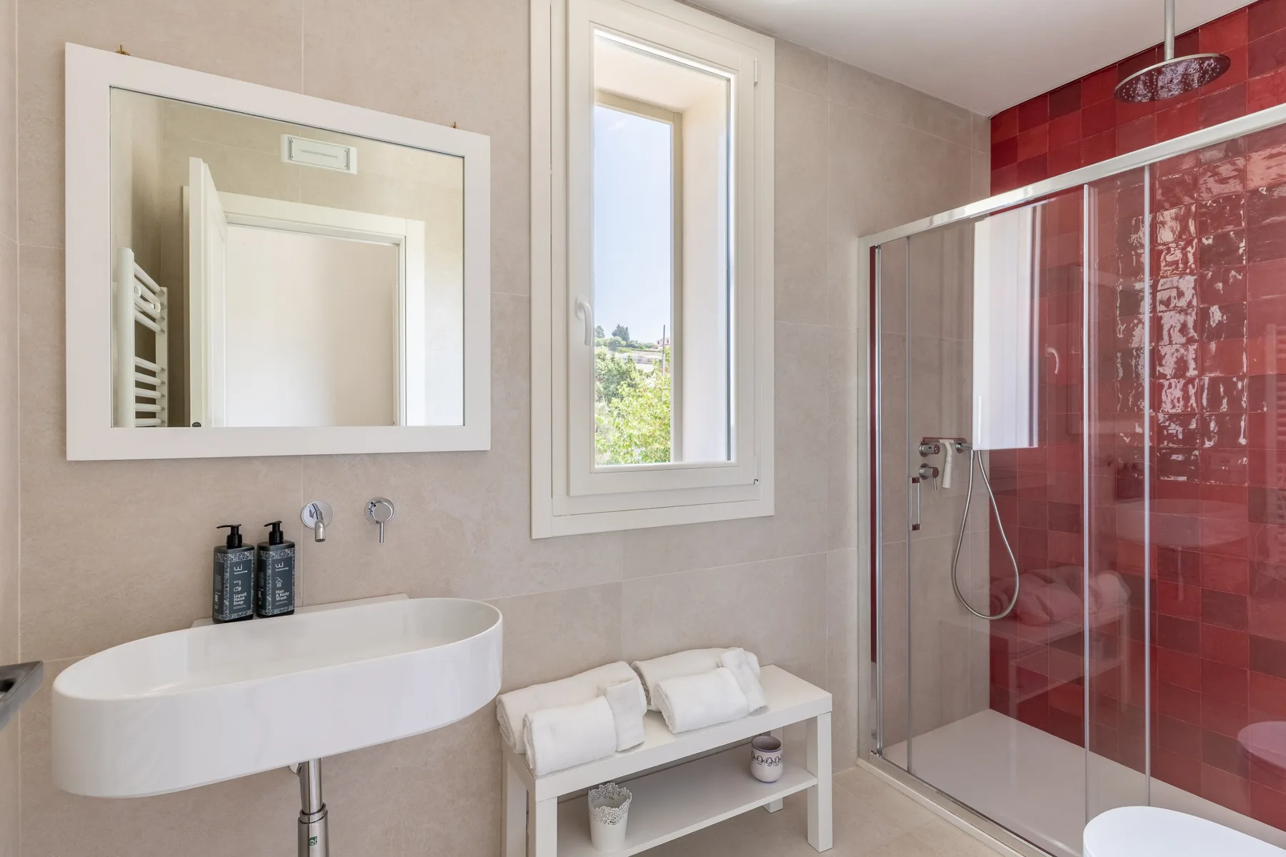 Un baño con un lavabo suspendido, una ventana y una ducha de vidrio.