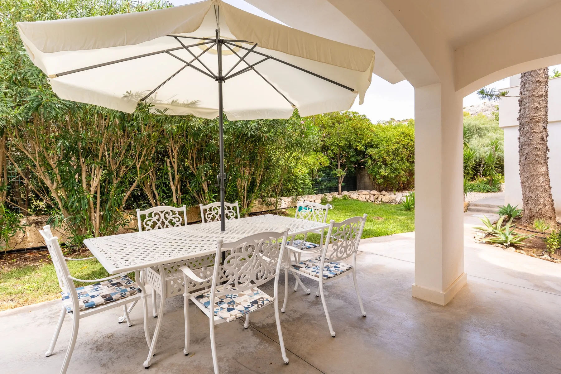 Una zona de comedor exterior cubierta con una mesa y vegetación de jardín.