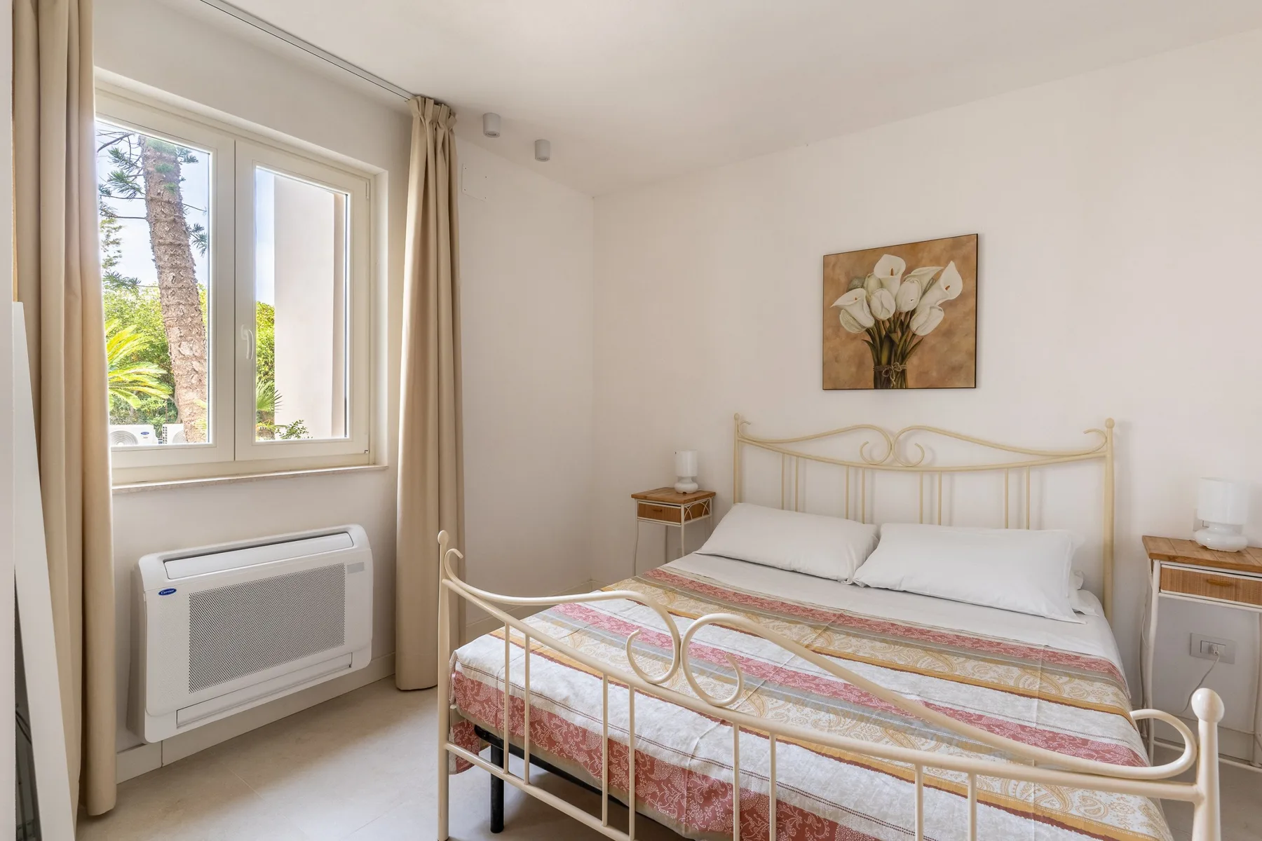 Un dormitorio luminoso con una cama junto a una ventana grande.