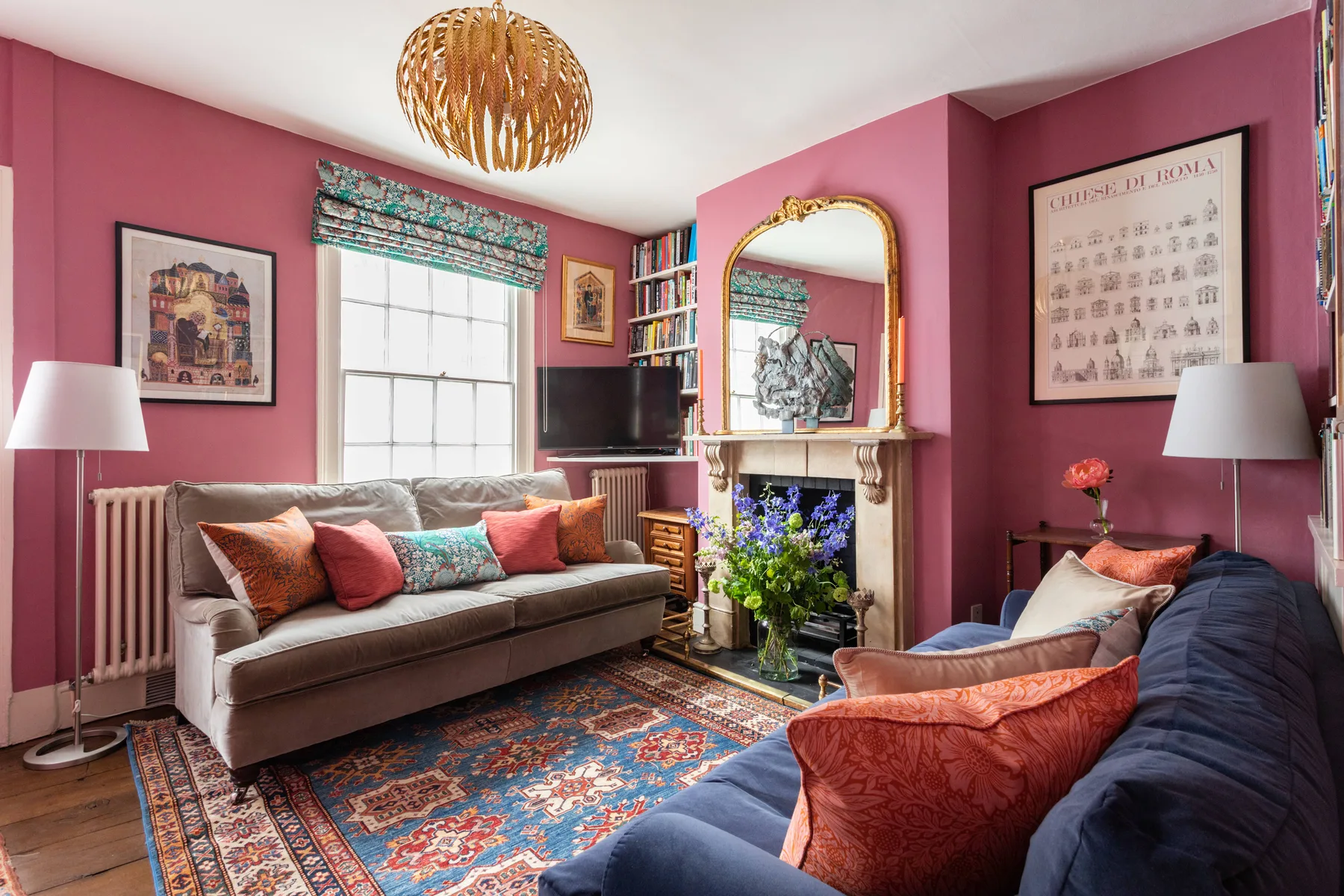 A colorful living room with seating, a fireplace, and a patterned rug.
