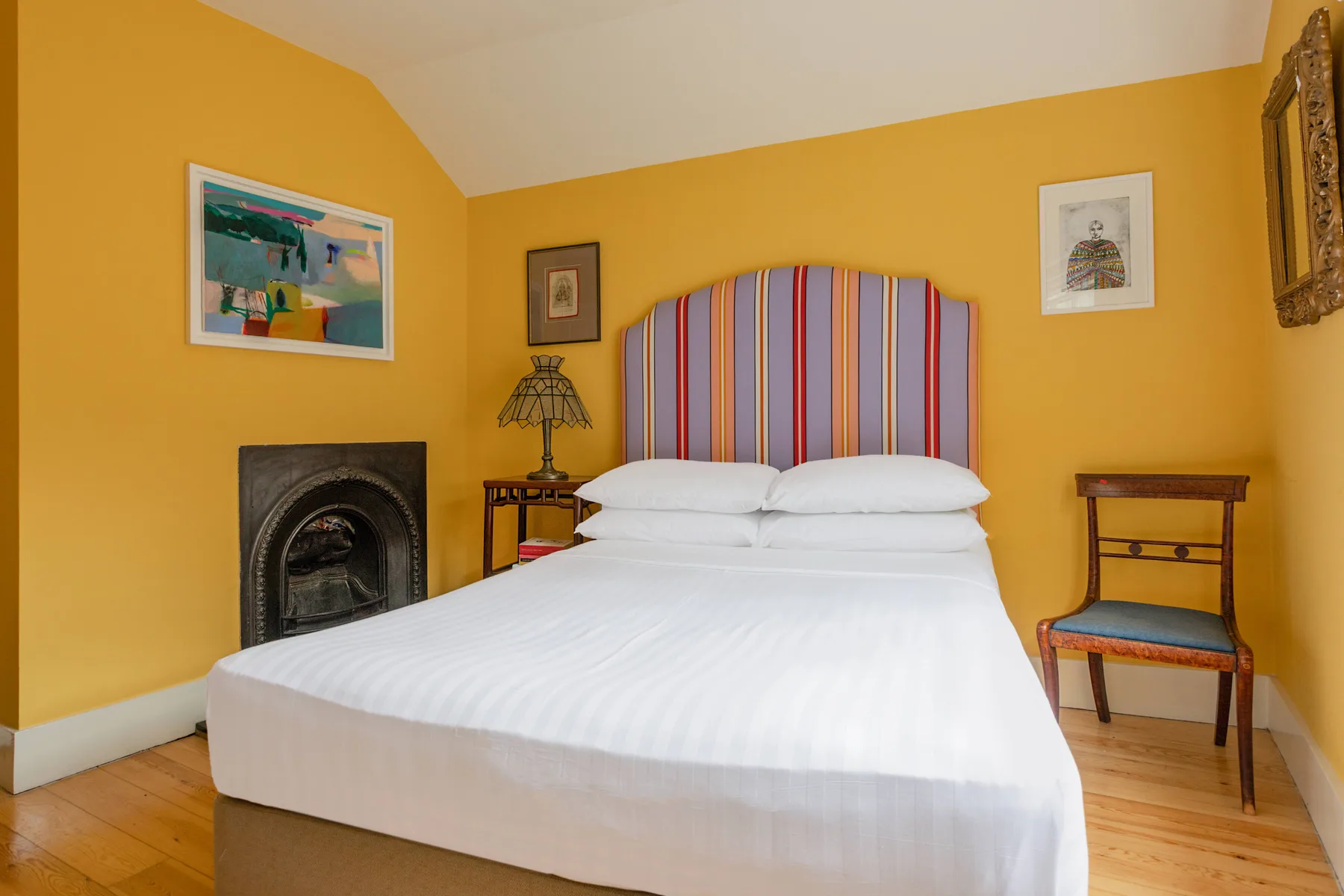 A bedroom with a neatly made bed and a colorful striped headboard.