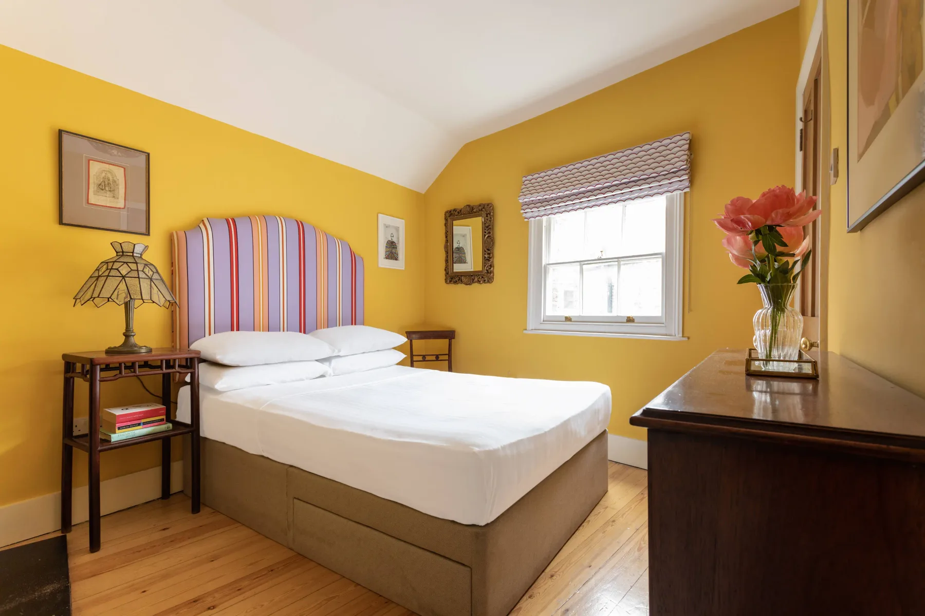 A bedroom with a bed, yellow walls, and a window.