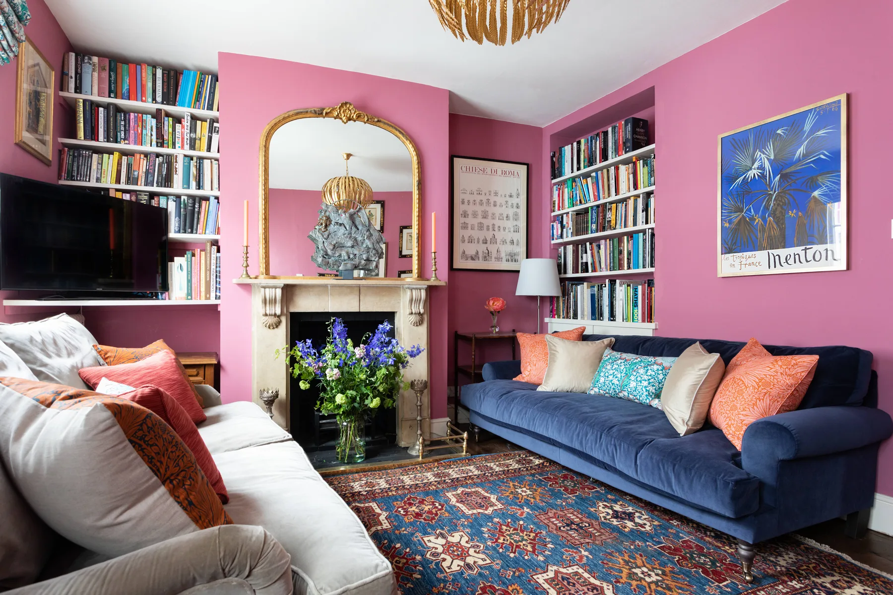 A colorful living room with bookshelves, a fireplace, and upholstered seating.