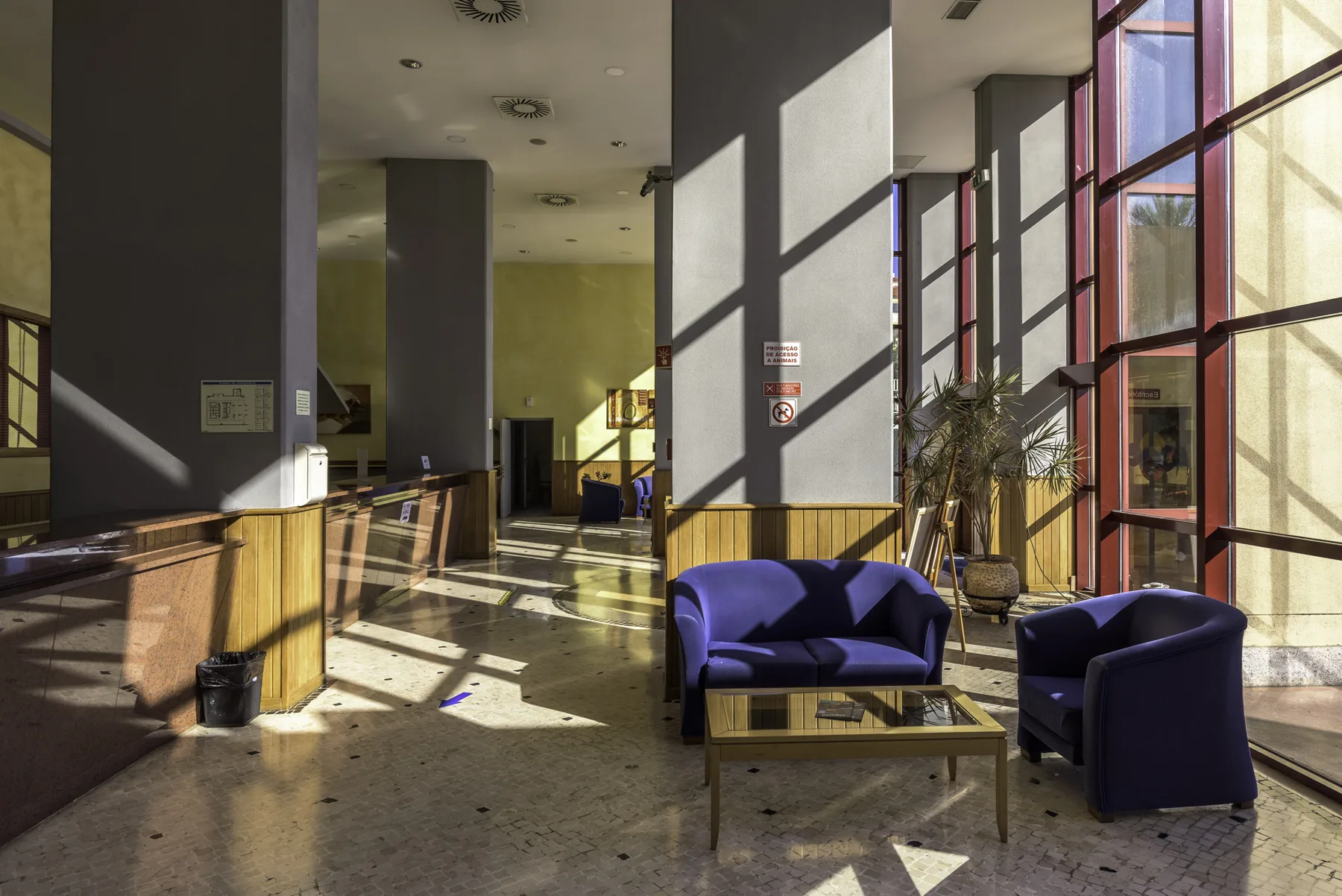 A bright lobby with reception counters and seating beside tall windows.