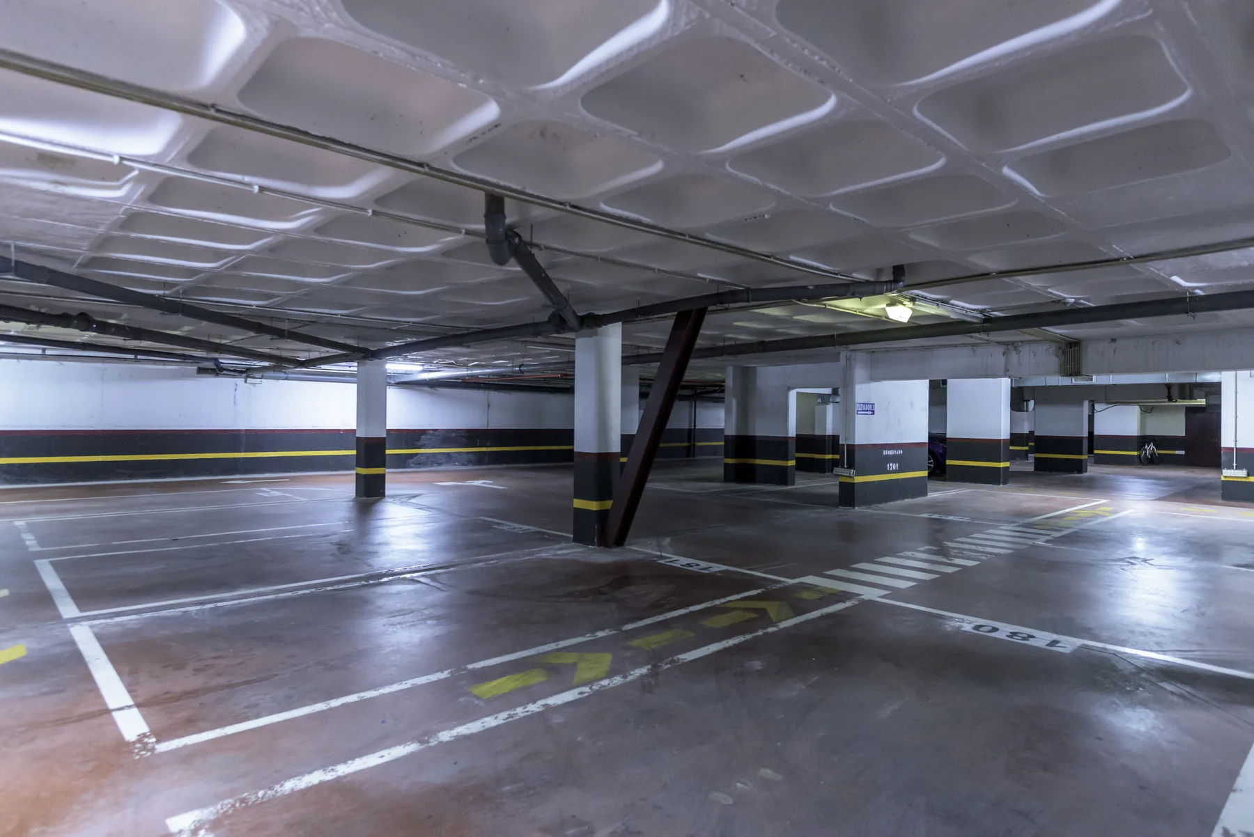 An indoor parking garage with painted parking spaces and support columns.