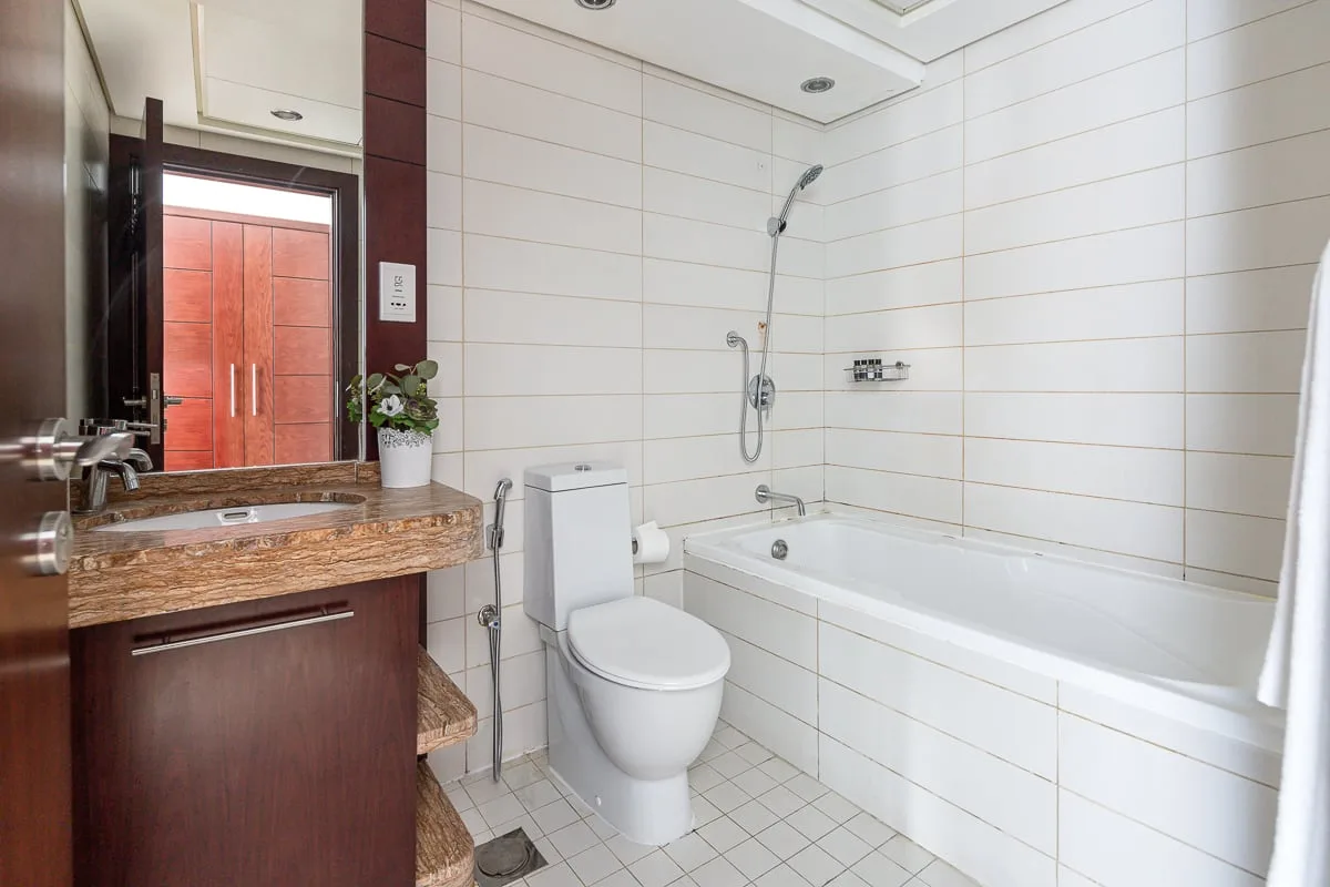 A tiled bathroom with a bathtub, shower, toilet, and sink.