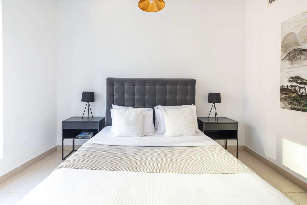 A bright bedroom with a neatly made bed and matching bedside tables.