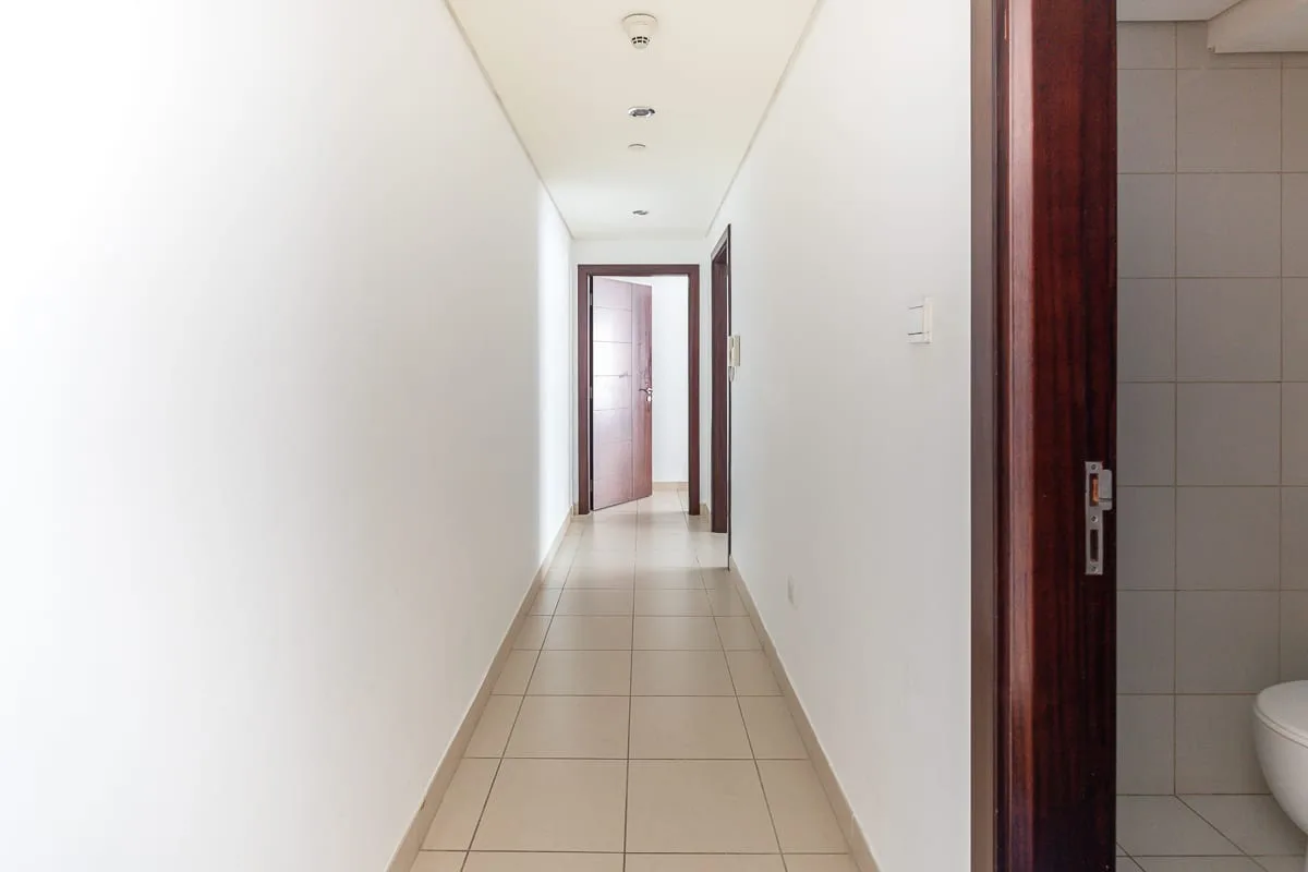 A tiled hallway leads to an open doorway, with a bathroom visible beside it.