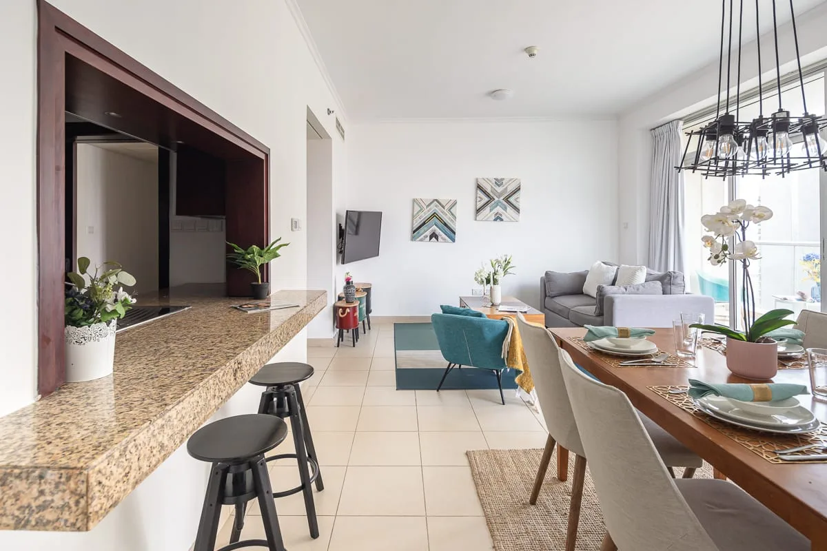 A bright open-plan living and dining area with a kitchen counter and seating.