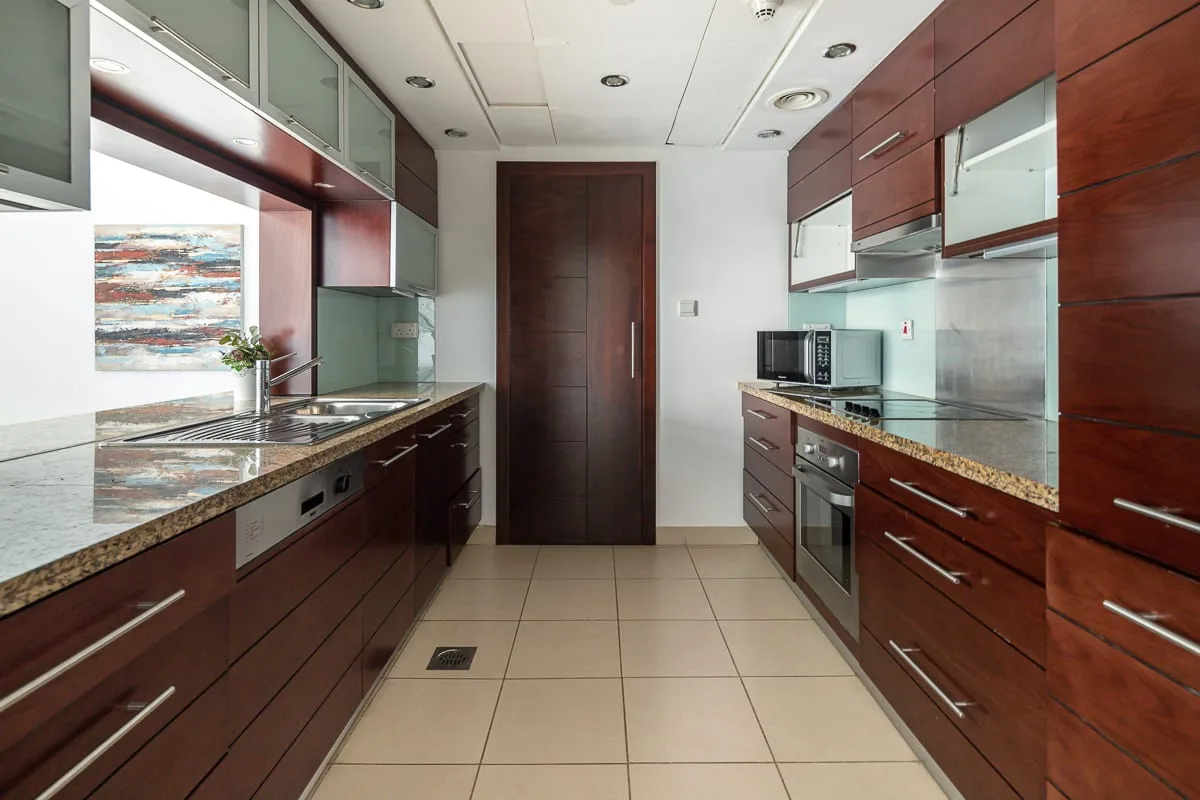 A galley kitchen with dark wood cabinets and countertops along both sides.