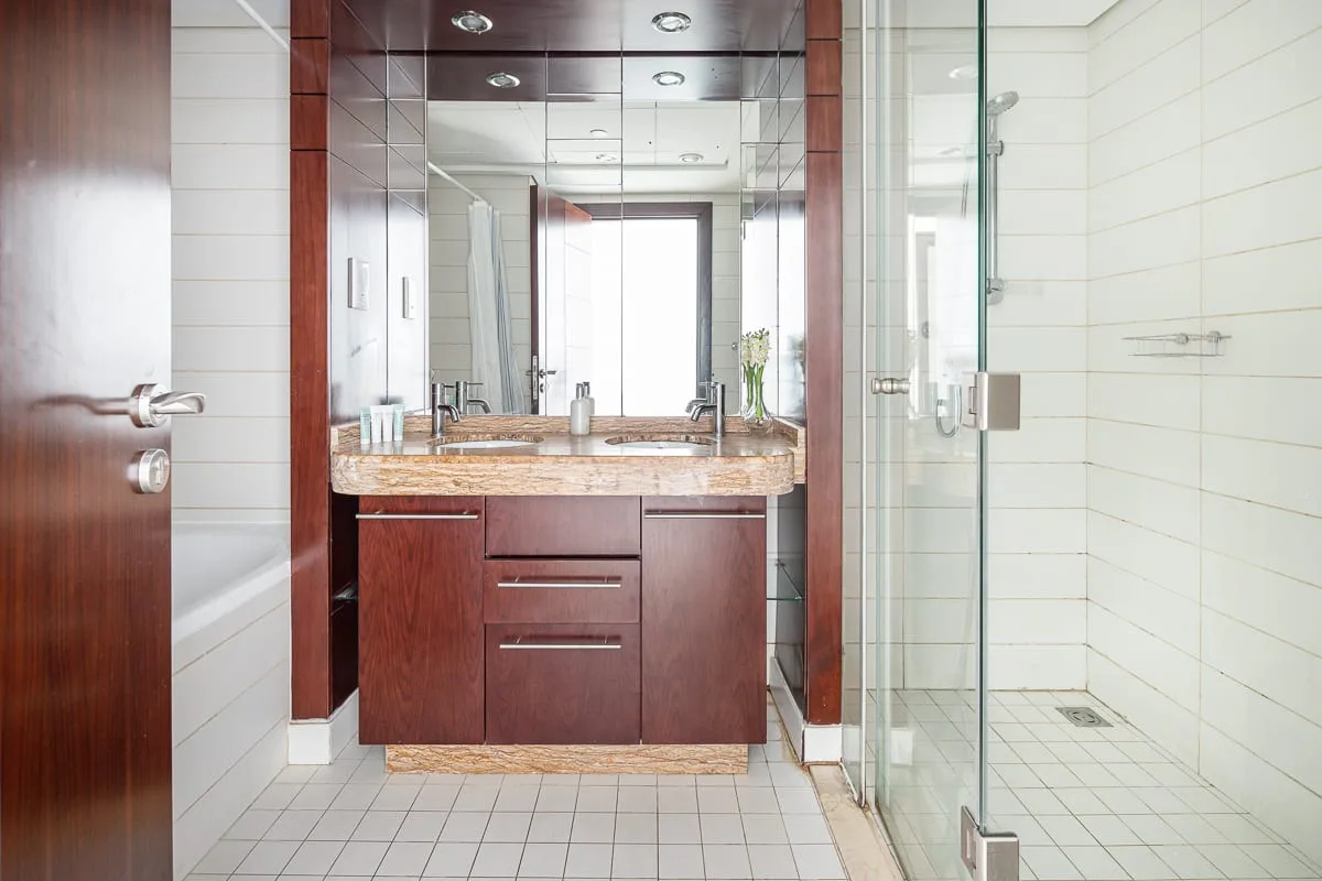 A bathroom vanity with a sink and a glass-enclosed shower.