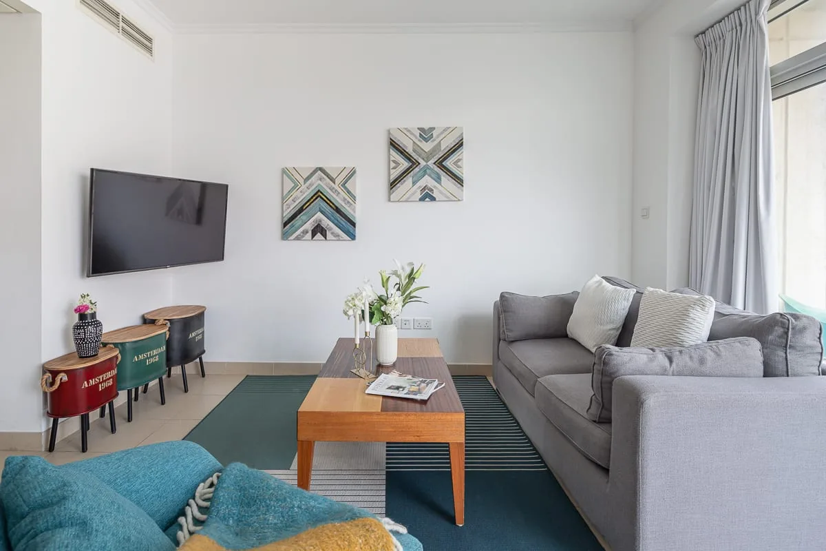 A living room with gray seating, a wooden coffee table, and wall-mounted television.